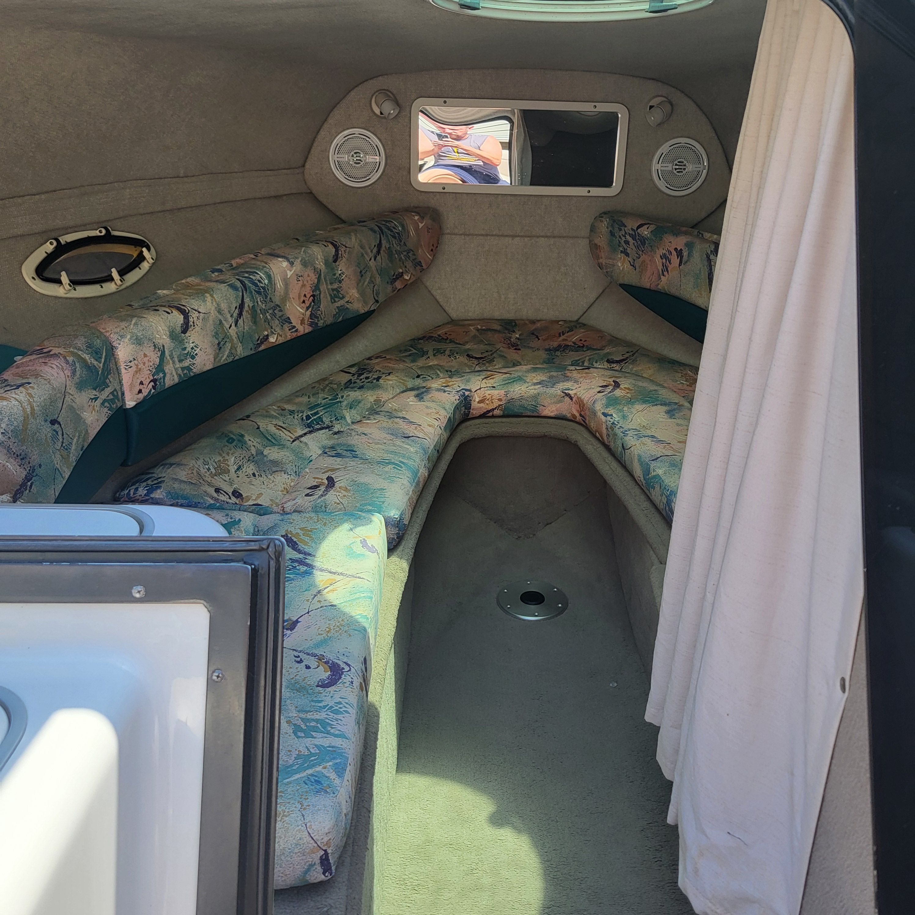 Interior of a 1996 Four Winns 245 Sundowner with patterned upholstery and a small window.