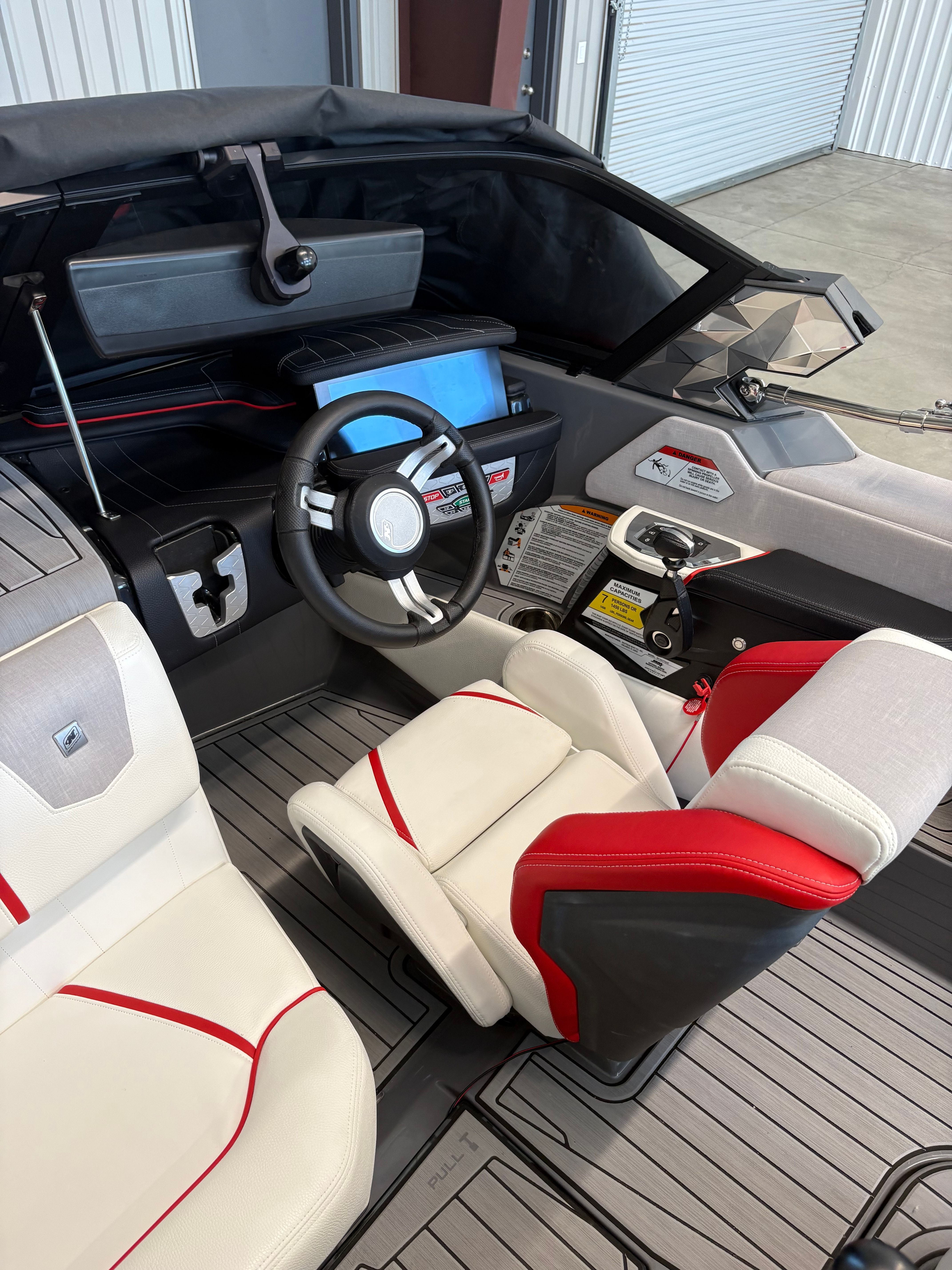 Interior of a modern boat with white and red seats and a sleek helm station.