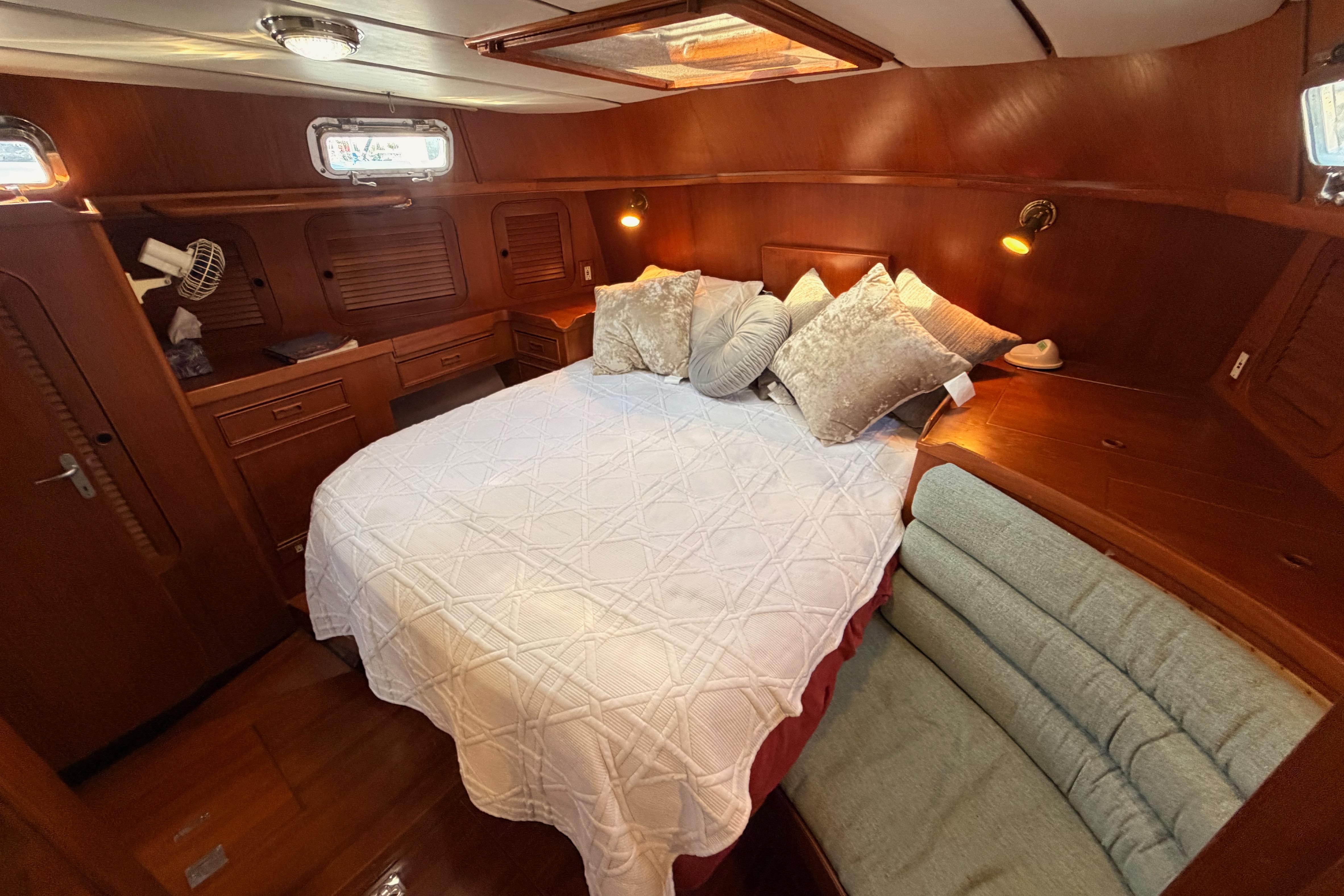 Luxurious cabin interior of a 1991 Hylas 51 yacht with cozy bedding and wooden furnishings.