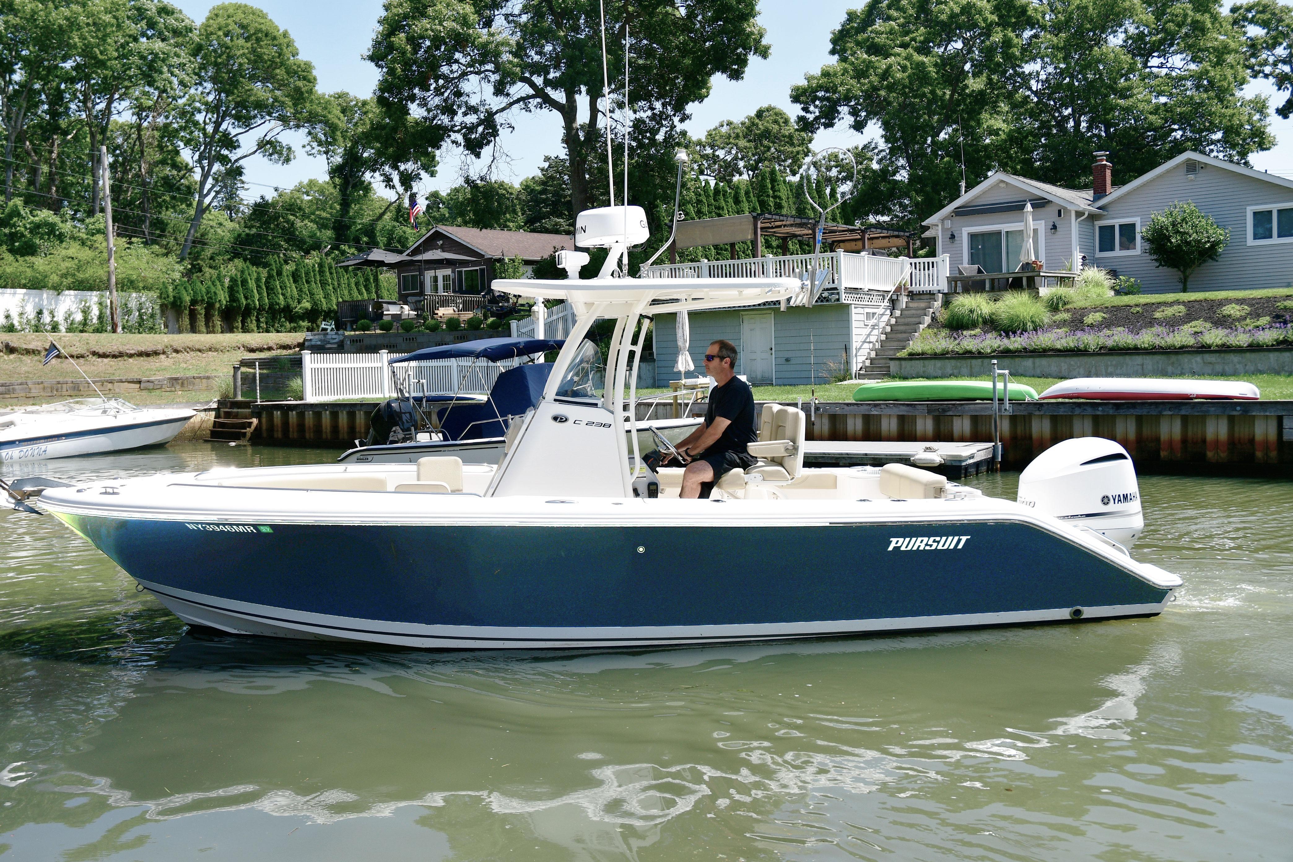 2020 Pursuit C 238 Center Console boat cruising near waterfront homes.