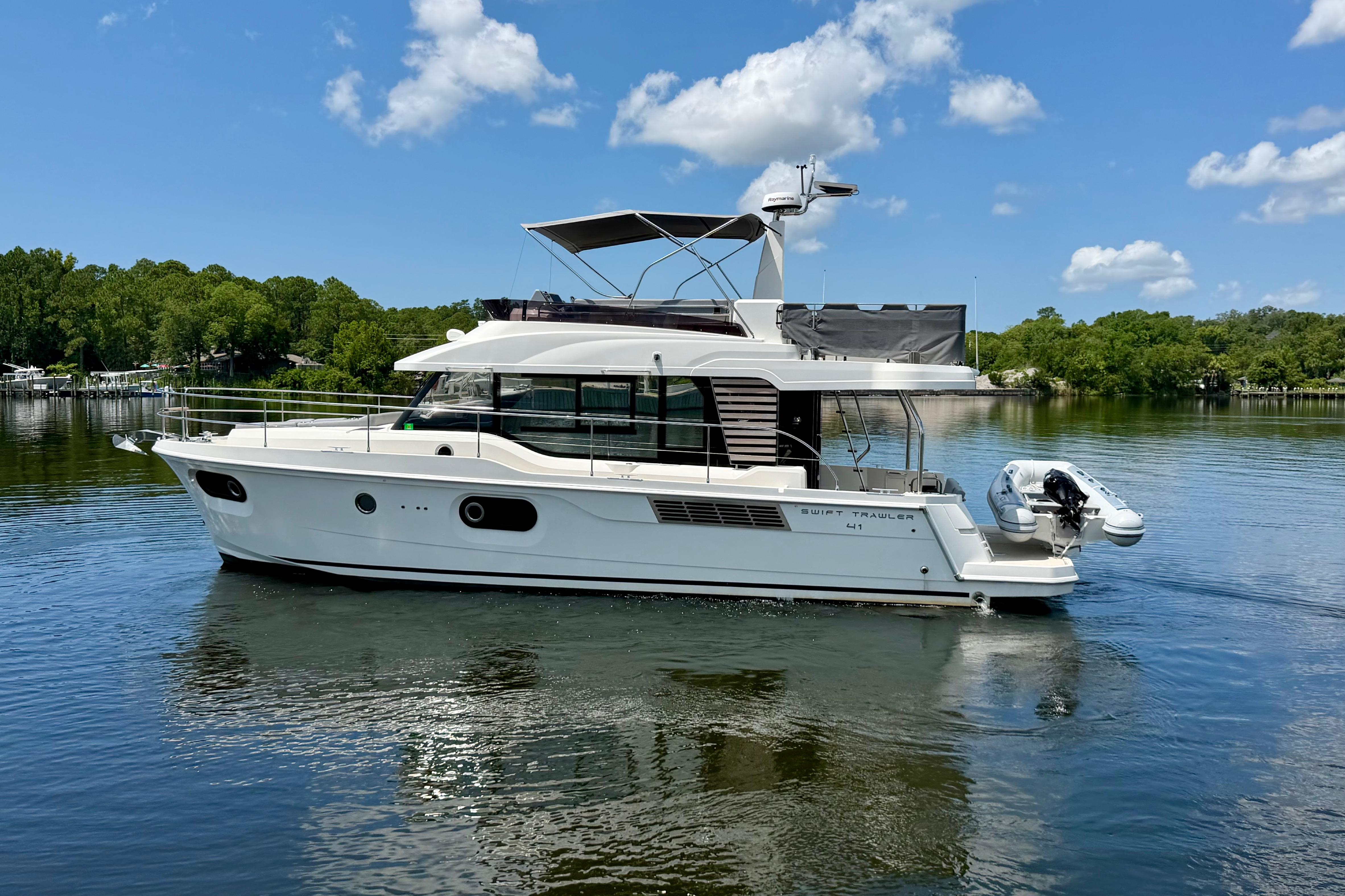 2025 Beneteau Swift Trawler 41 Fly on a serene lake under a clear blue sky.