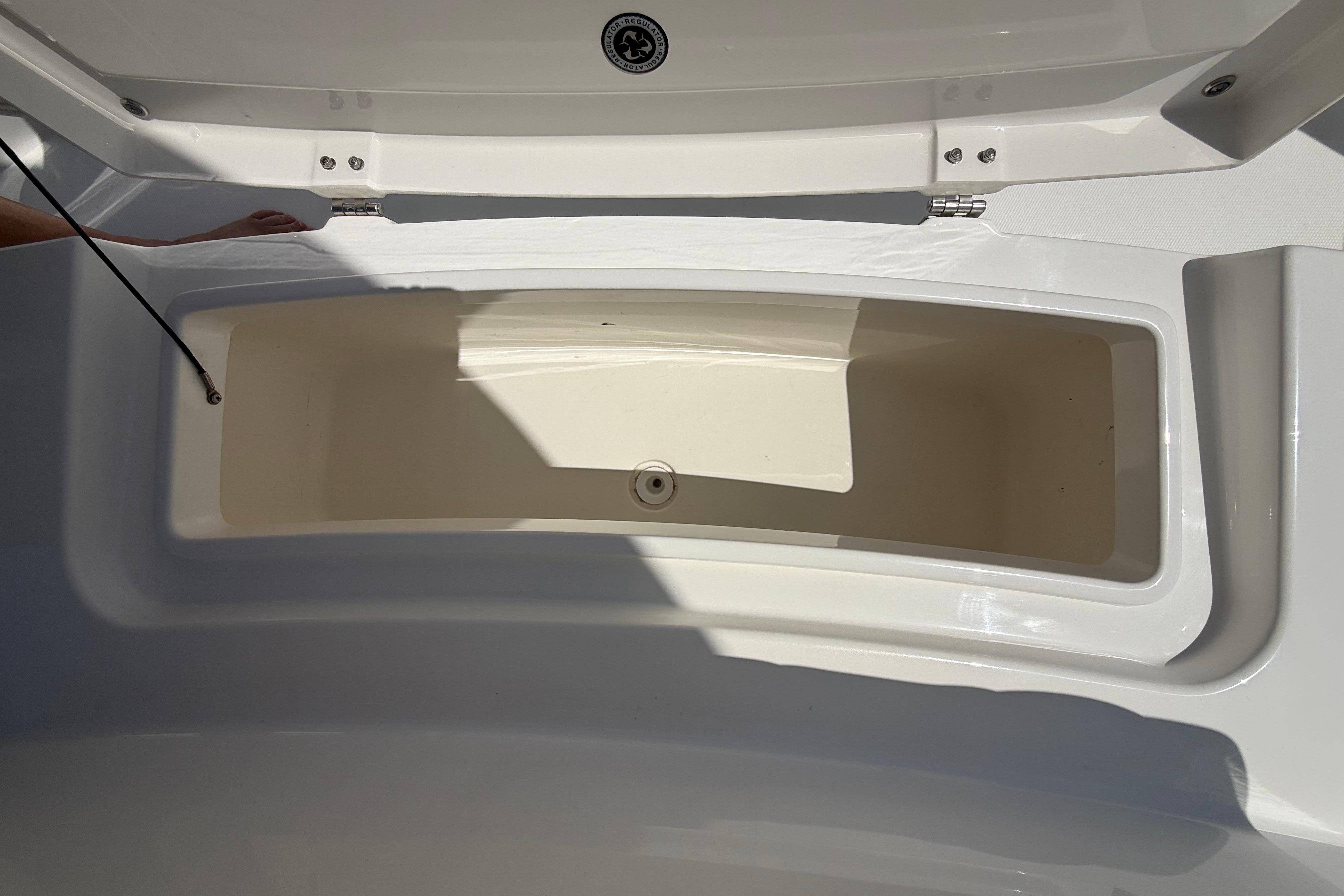 Open storage compartment on 2023 Regulator 26XO boat, showcasing interior space.