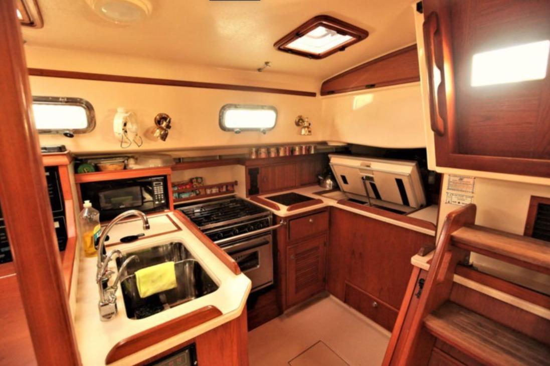 Interior of 2000 Island Packet 420 yacht kitchen with wooden cabinetry and modern appliances.