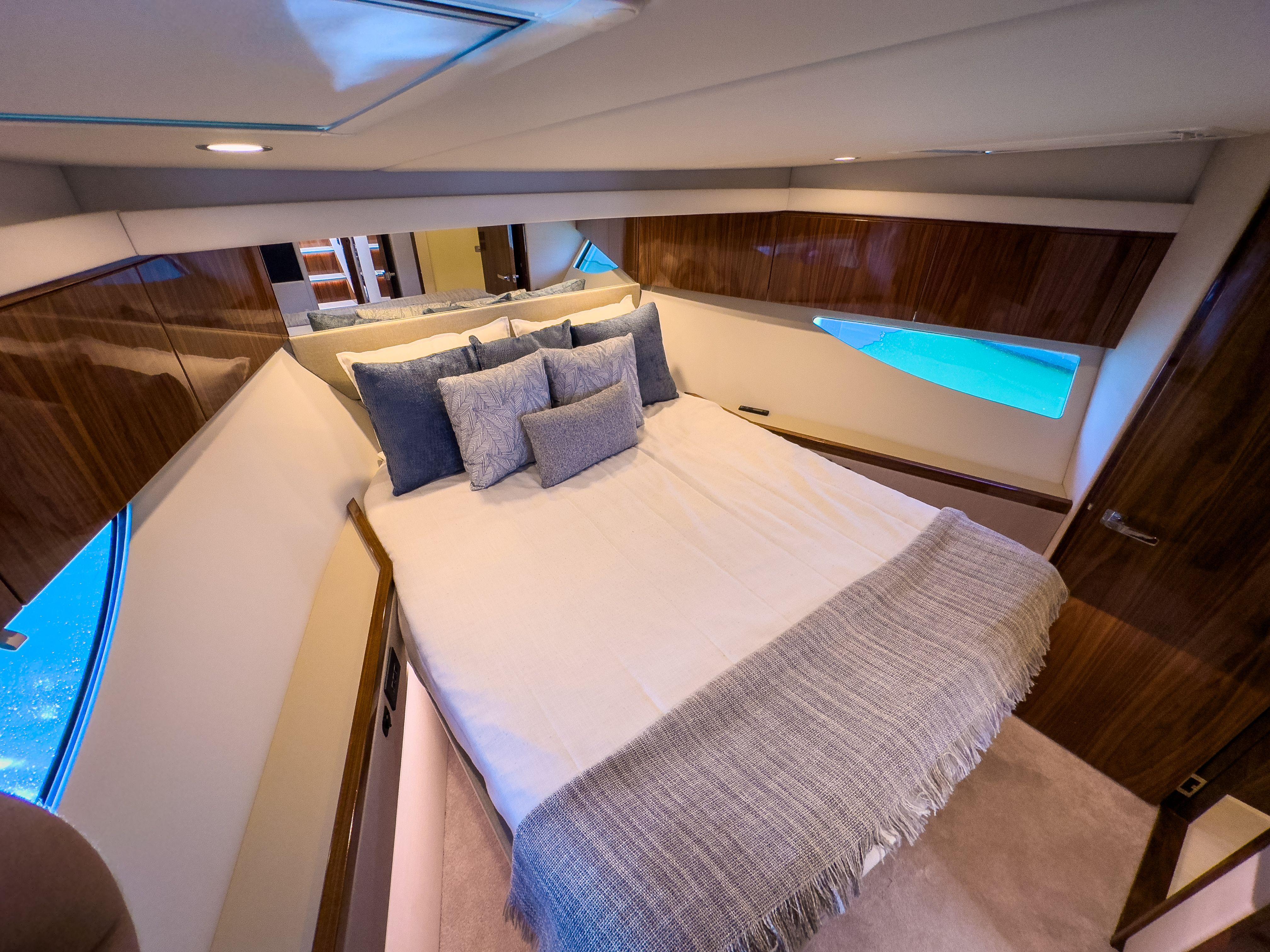 Luxurious bedroom interior of 2024 Riviera 465 SUV yacht with elegant bedding and wood accents.