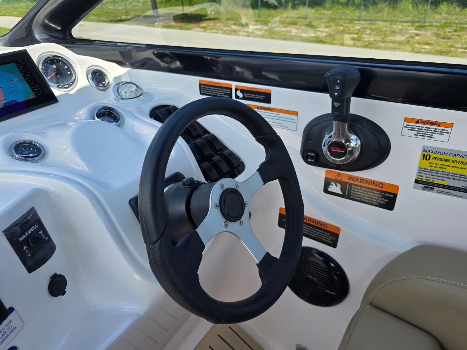 The image shows a boat's helm with a modern steering wheel and instruments.