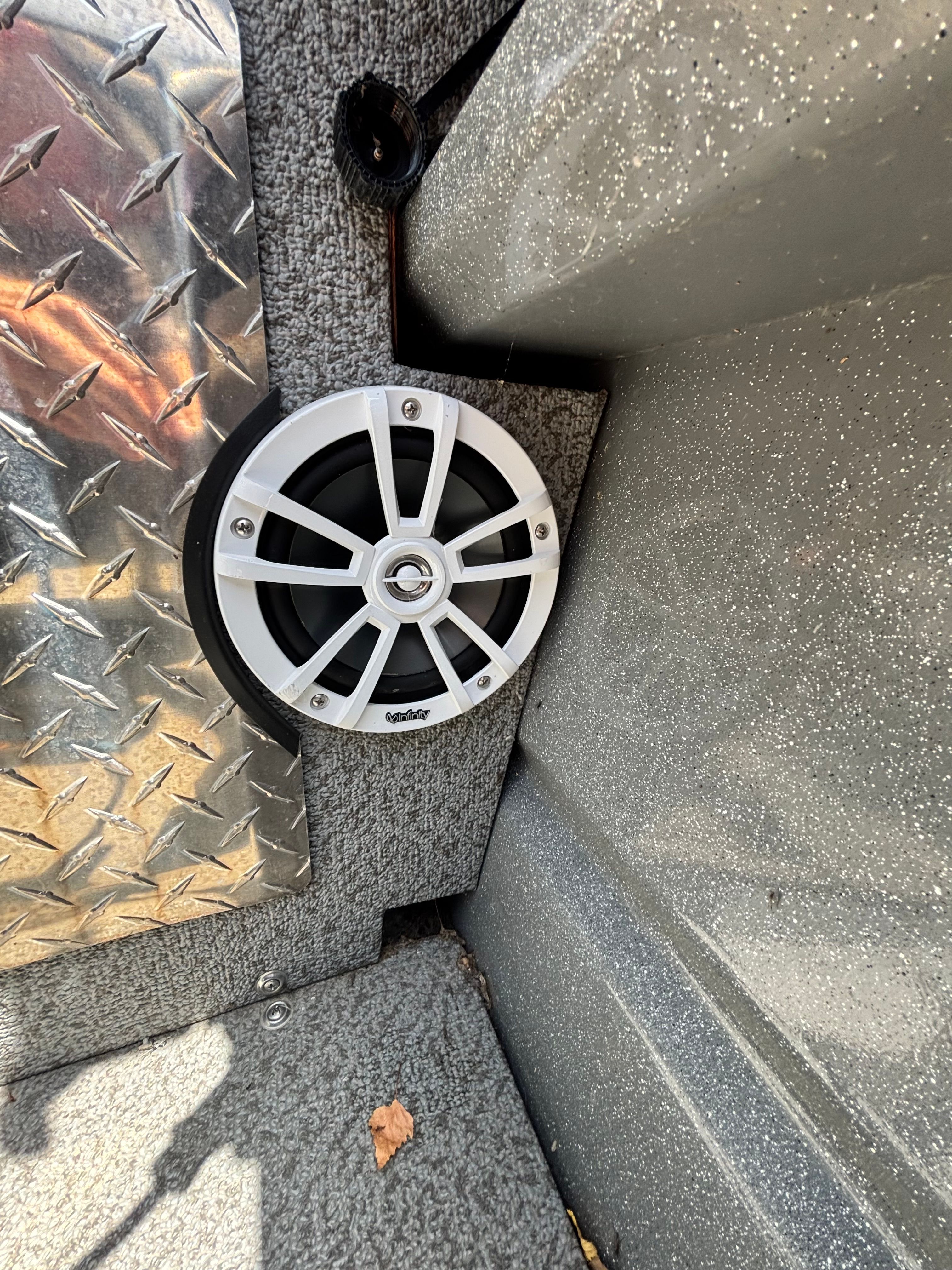 A speaker is mounted in the wall of a boat, surrounded by textured material.