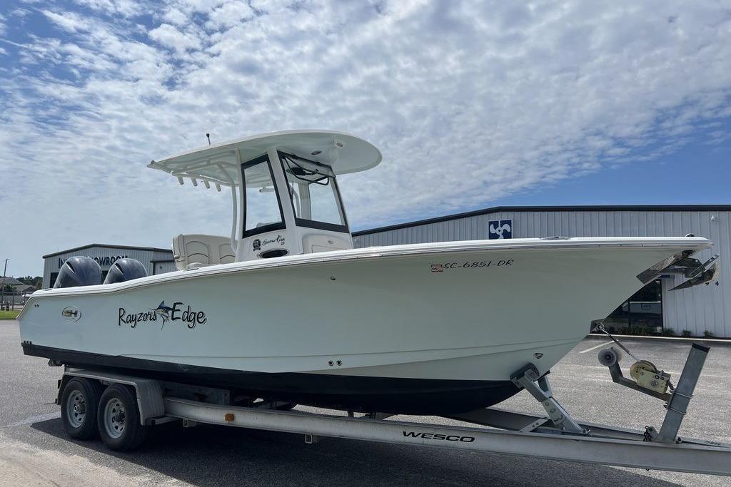 2021 Sea Hunt Gamefish 25 boat on trailer under cloudy sky.