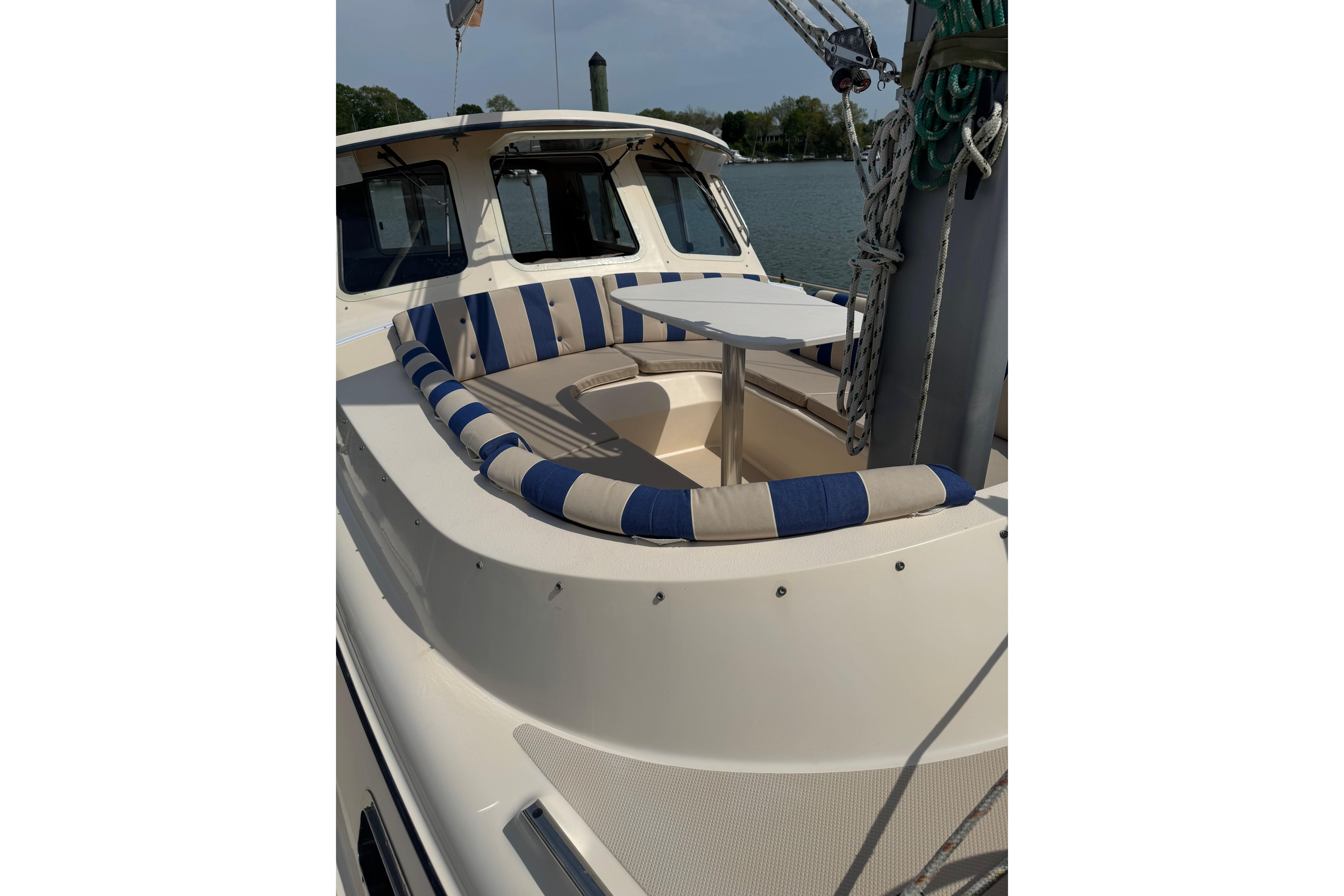2008 Island Packet SP Cruiser with striped seating and table on deck.
