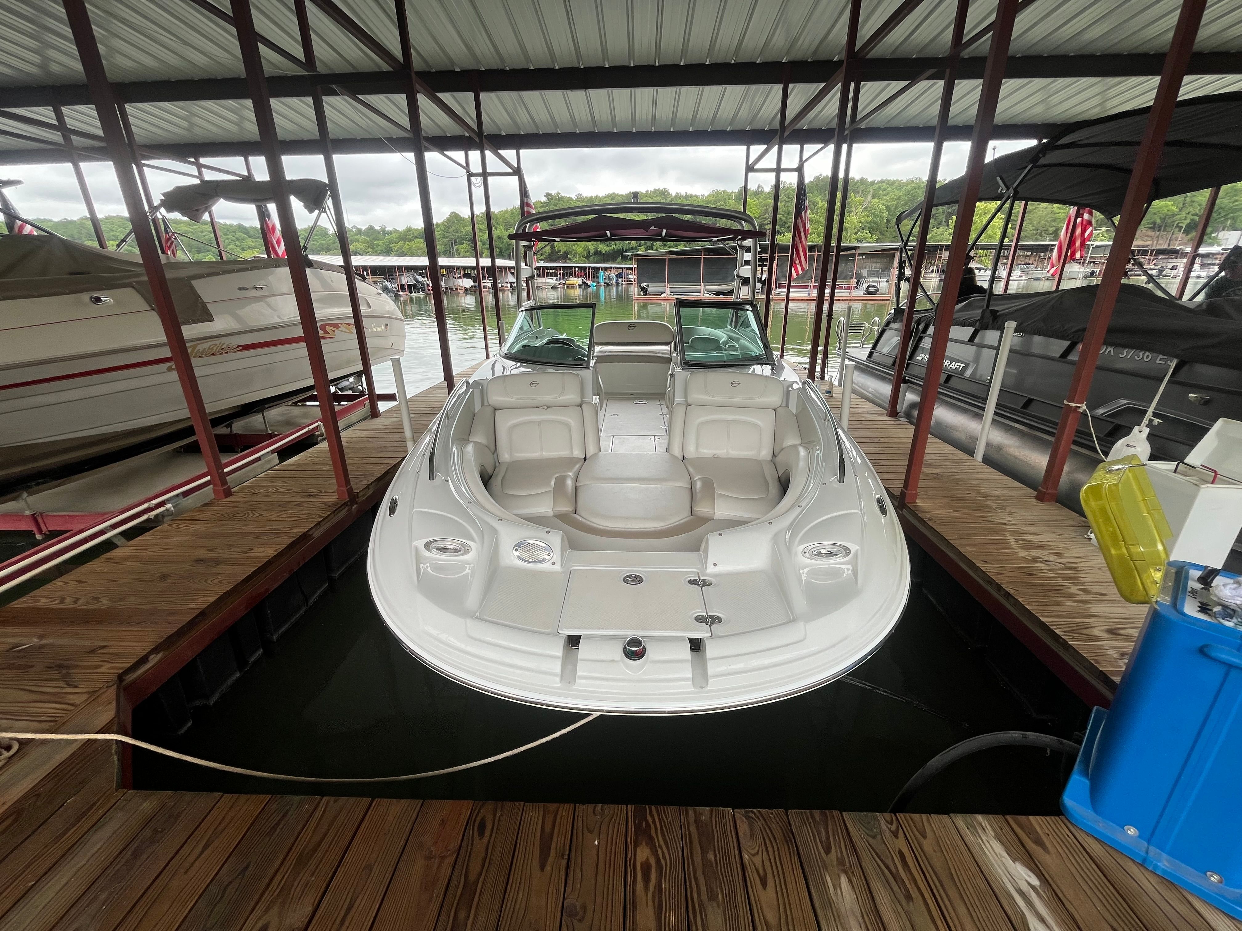 A 2008 Crownline 252EX boat is docked under a covered area. It features a white exterior.