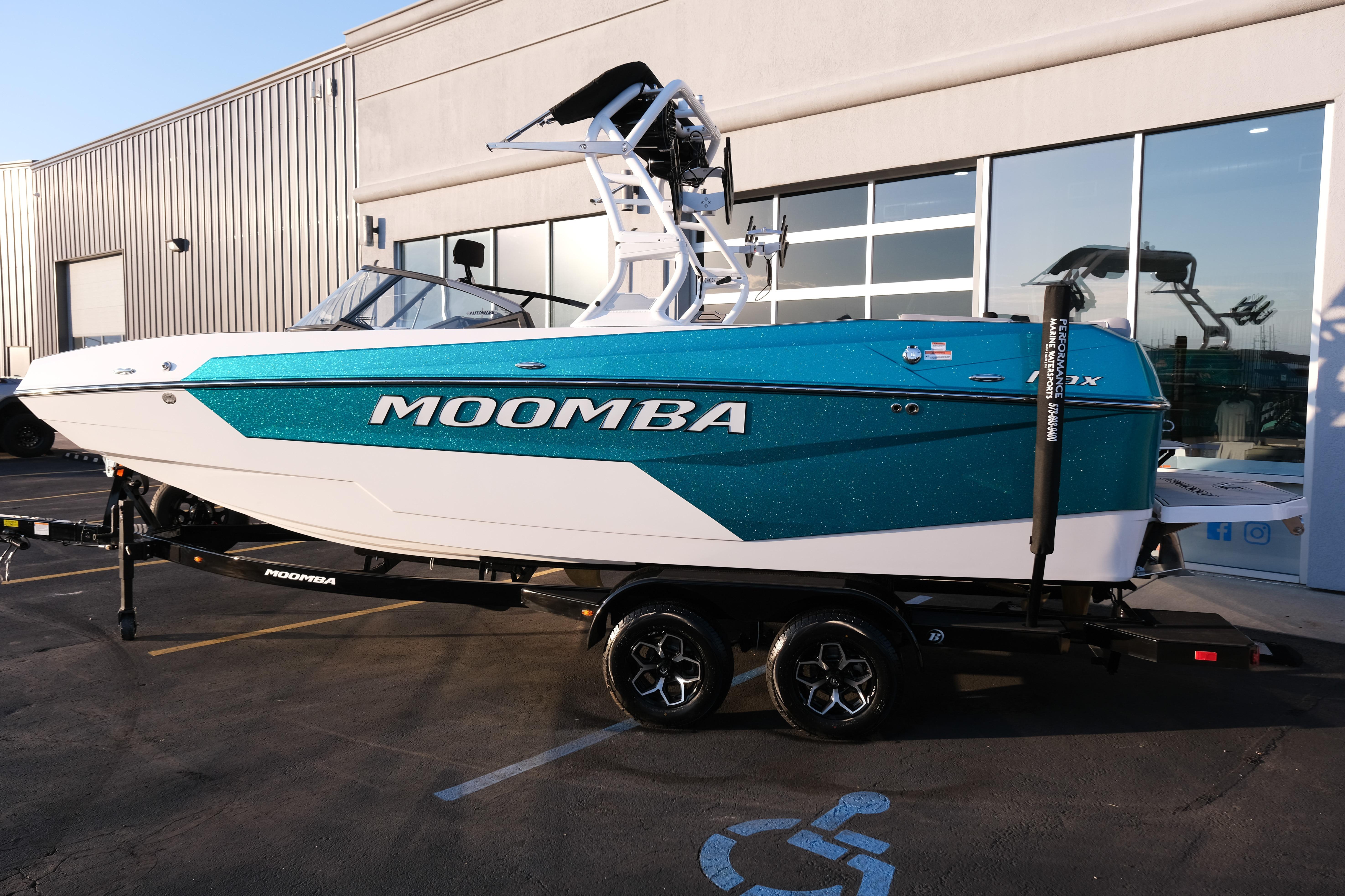 2026 Moomba Max boat in teal and white, parked outside a building.