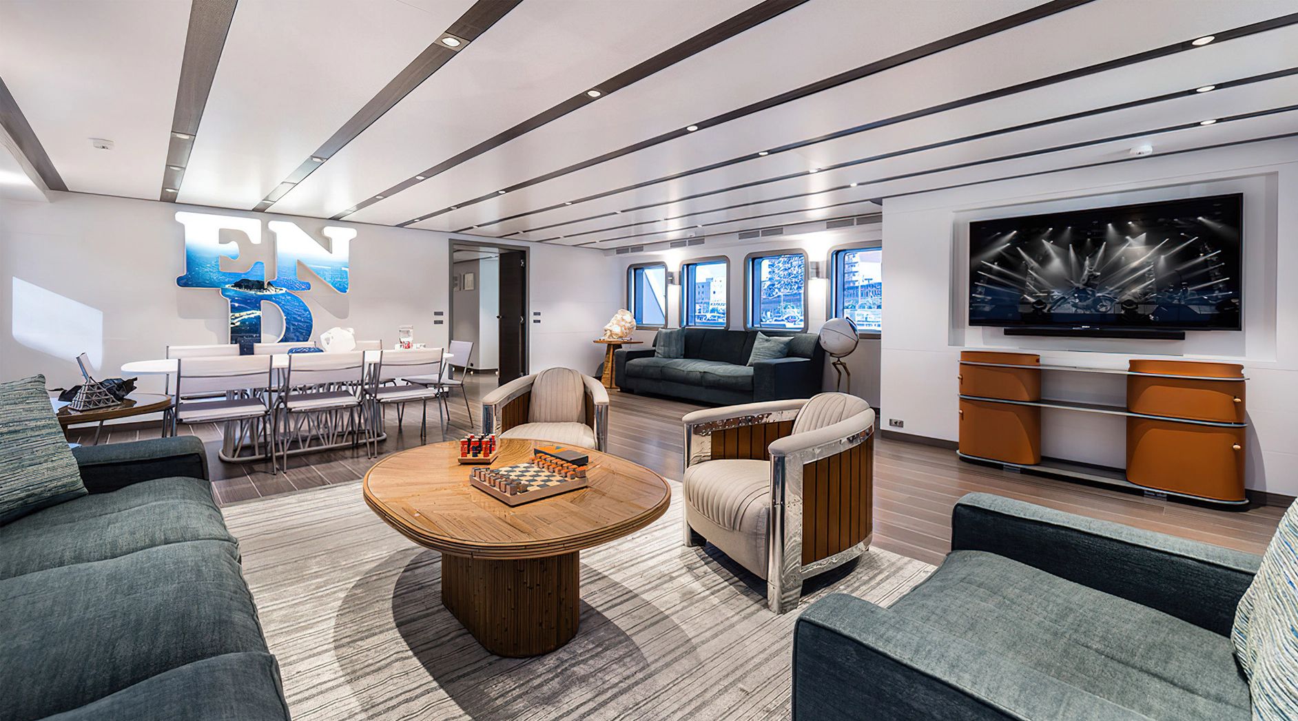Luxurious salon with modern furniture, large TV, and stylish decor on a yacht.