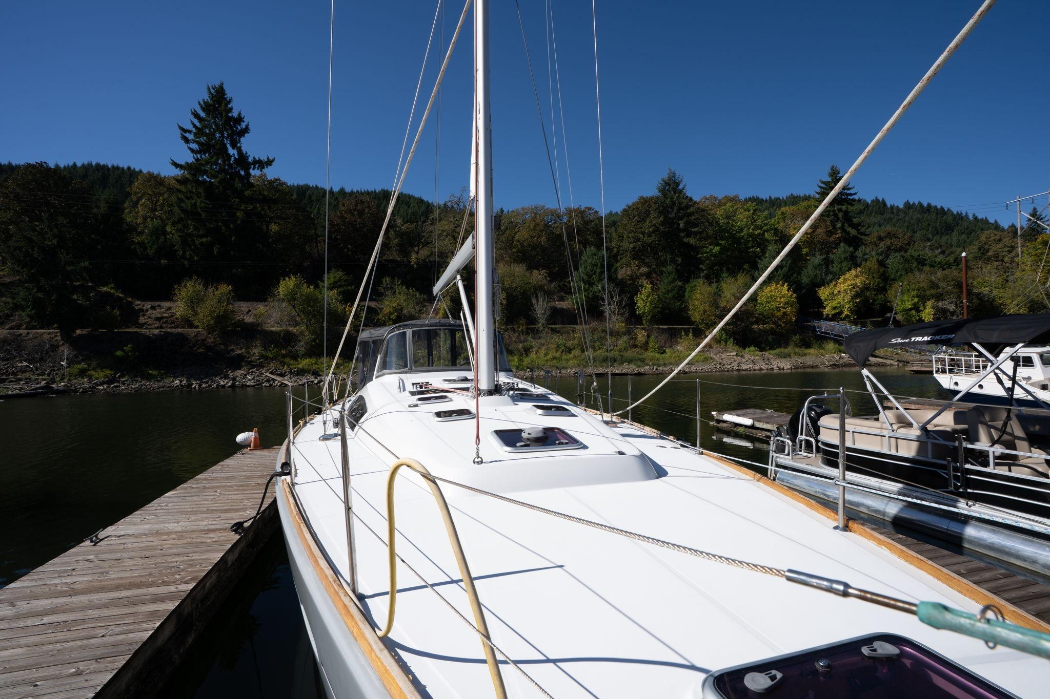 2013 Beneteau Oceanis 50 sailboat docked, surrounded by lush greenery and calm waters.