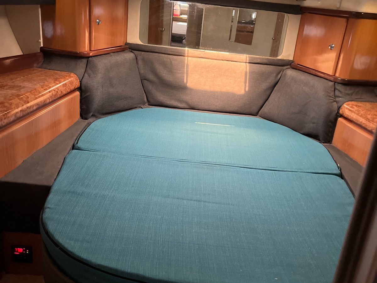 The cabin of a 1999 Sealine F44 with a large round bed and wooden furnishings.