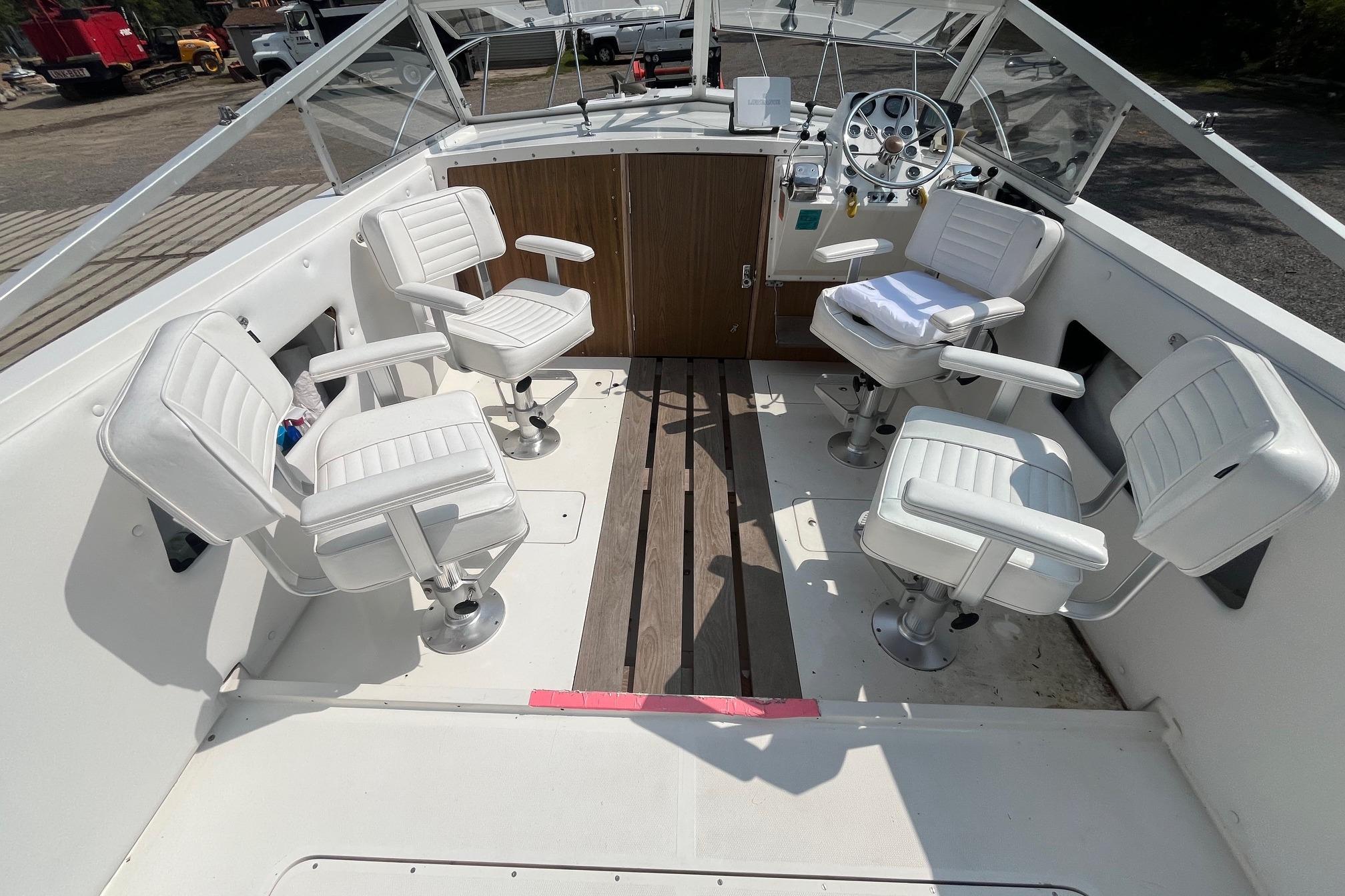 1975 Bertram 26 Moppie boat interior with white swivel chairs and wooden flooring.