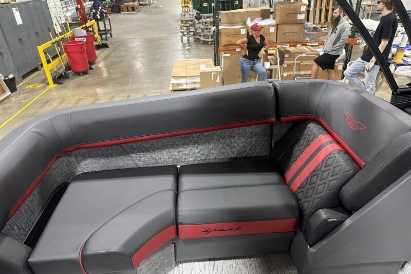 2026 Bennington 24 MFBSF boat interior with sleek gray and red seating in a warehouse.