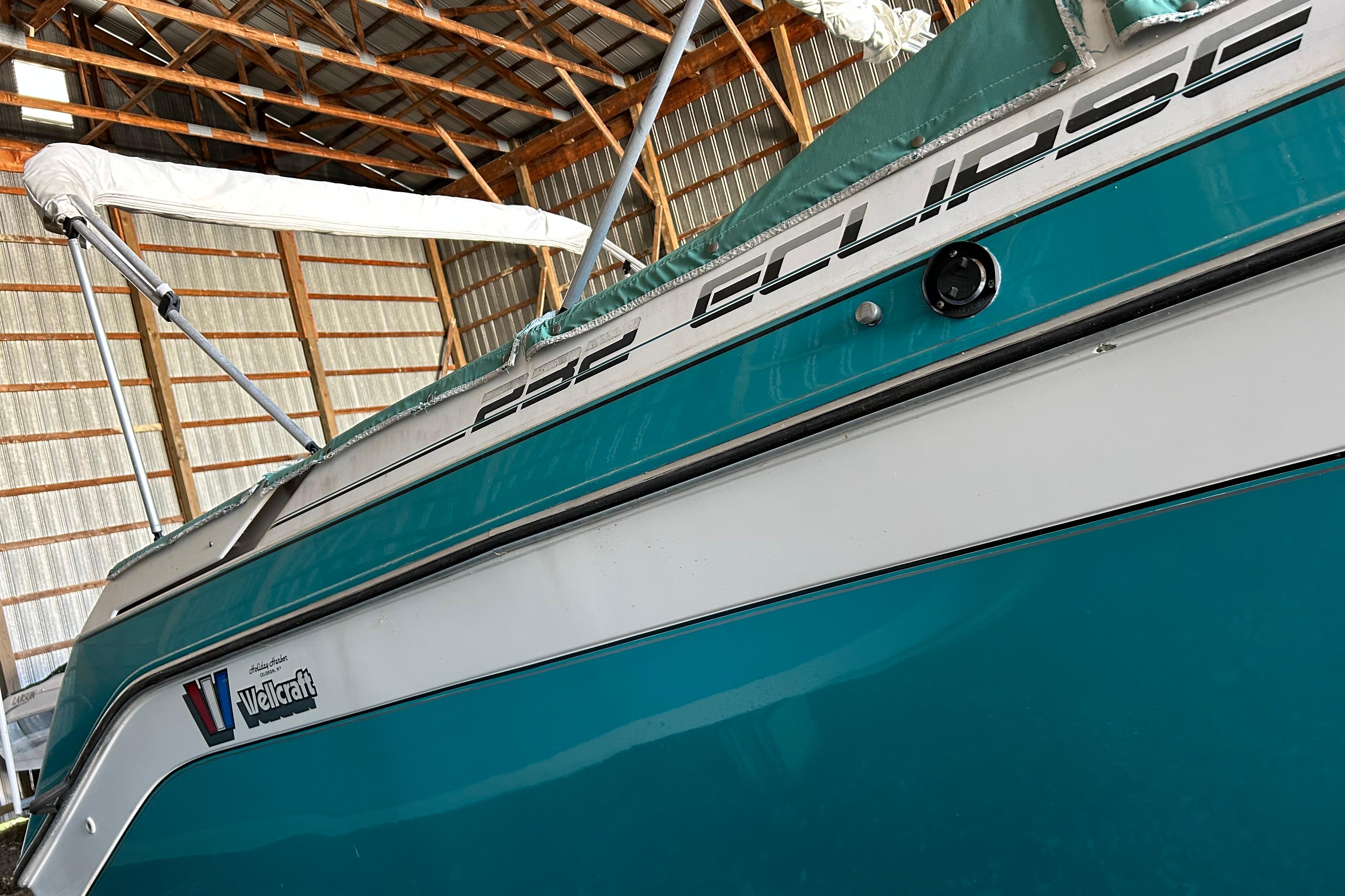 1991 Wellcraft 232 Eclipse boat in storage, showcasing teal and white exterior.
