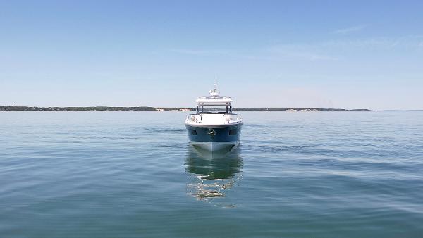 Front view of a 2025 Nimbus T11 boat on calm water under a clear sky.