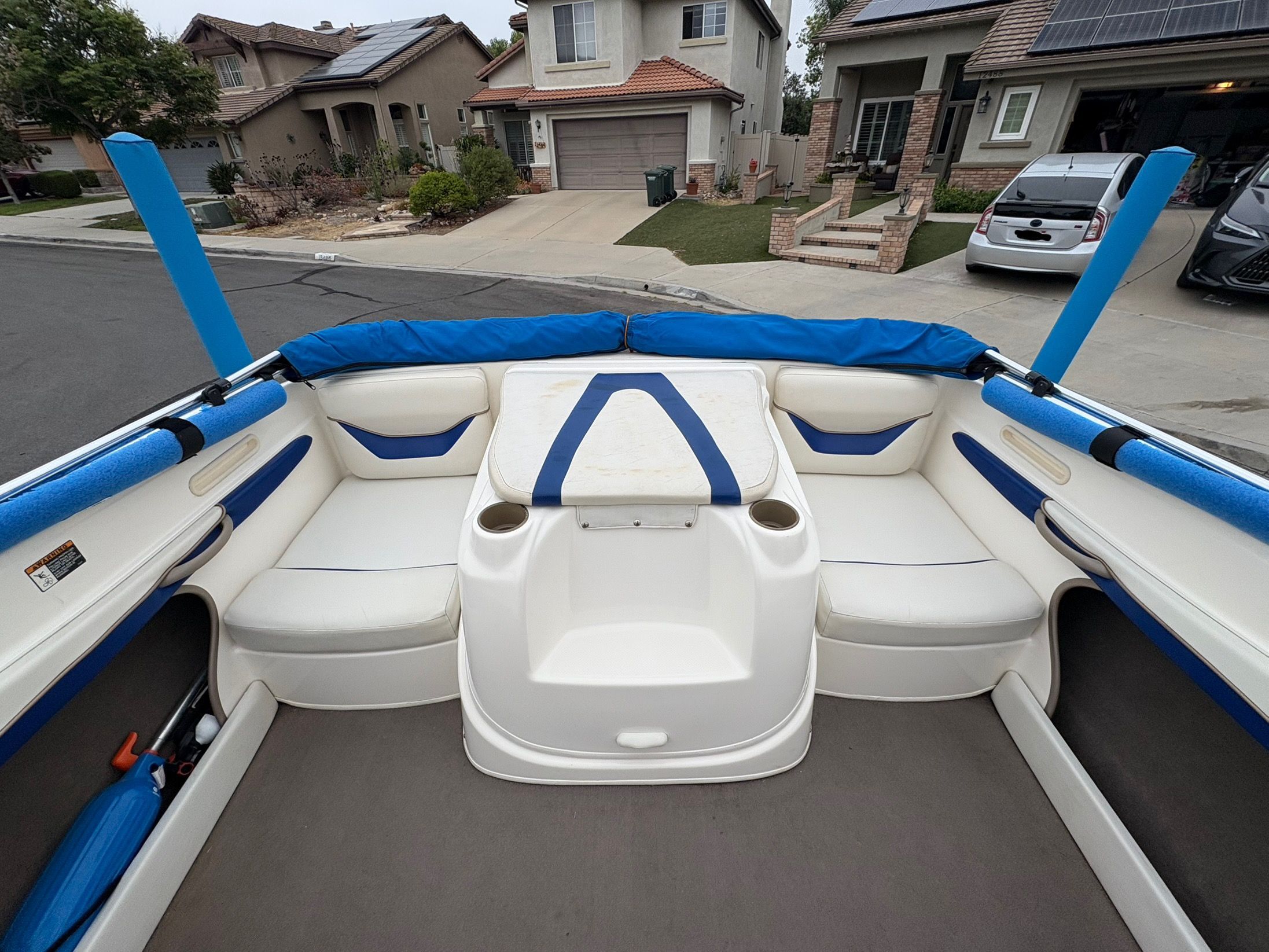 2003 Bayliner CAPRI 205 boat interior with white and blue seating, parked in residential area.