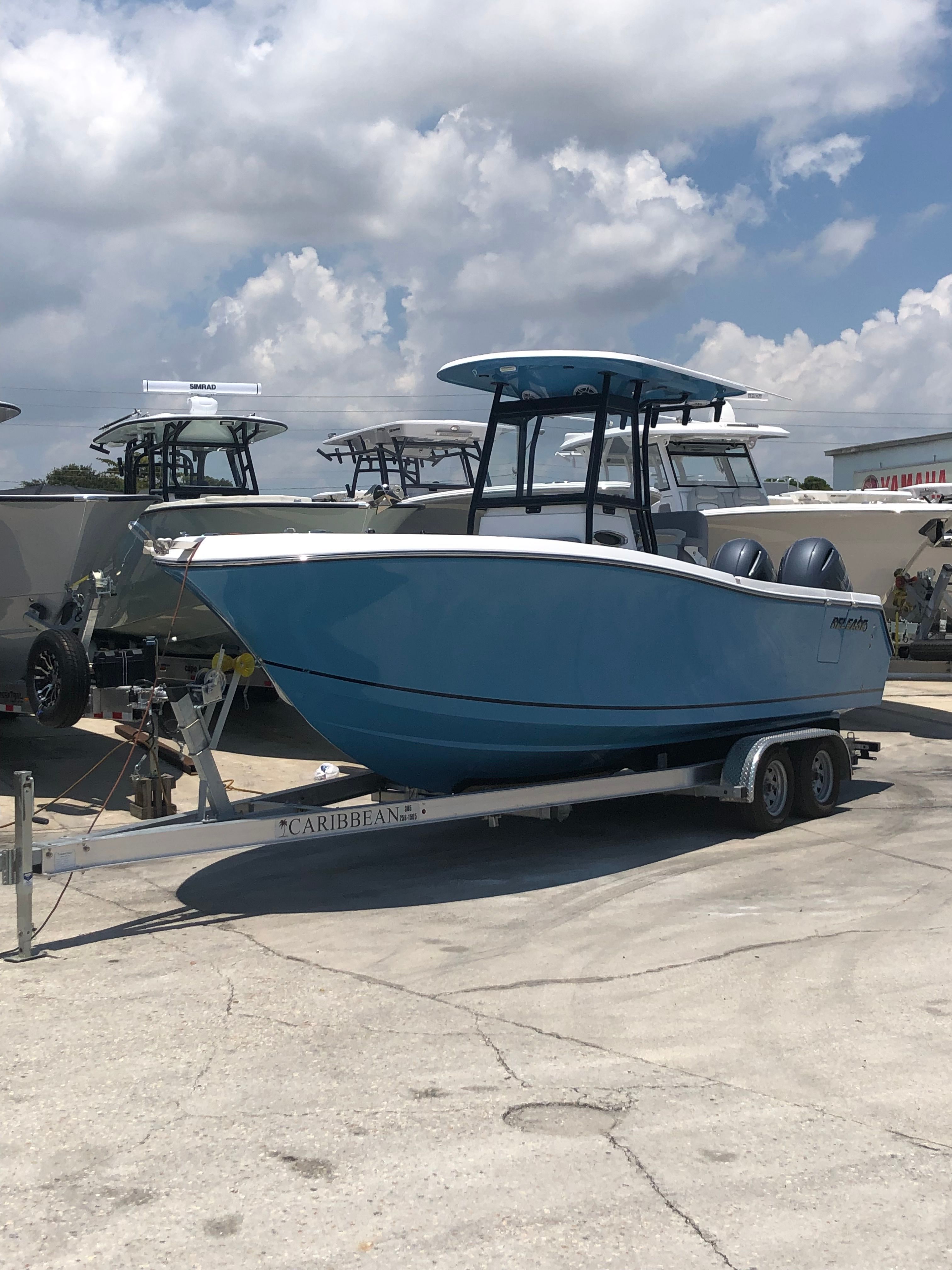 Blue Release 240 RX 2022 boat on trailer, cloudy sky.