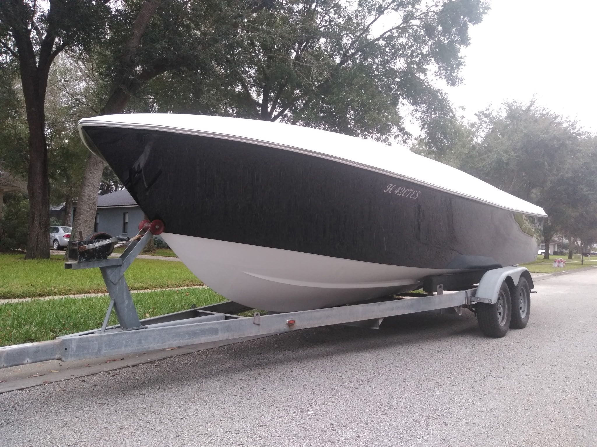 A 1985 Aquasport boat on a trailer, parked on a street.