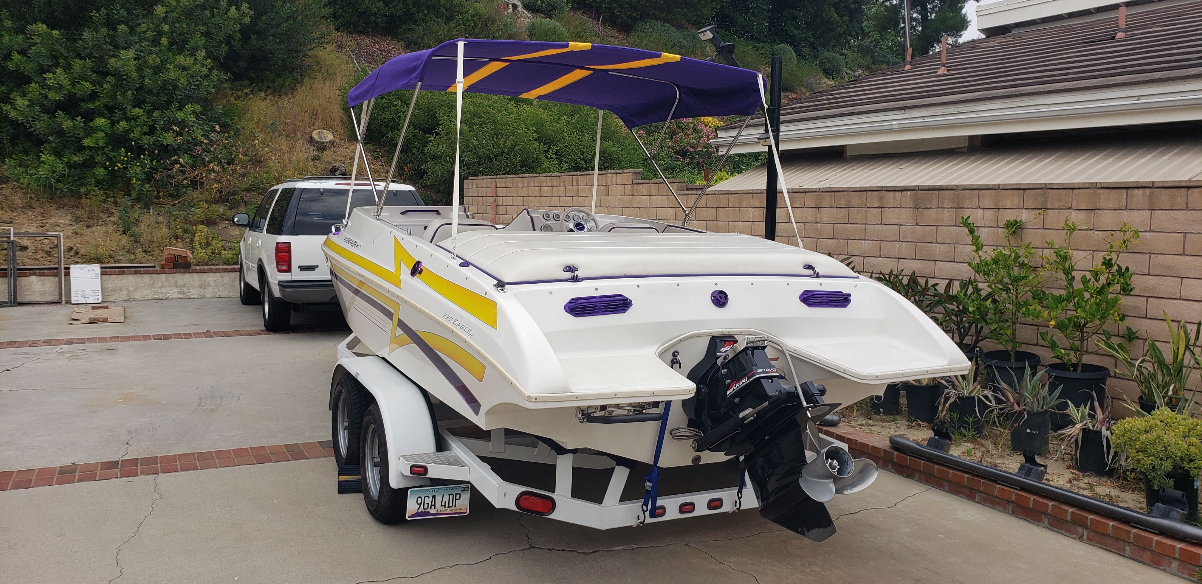 1999 Eliminator 220 Eagle XP boat with trailer, parked in a driveway.