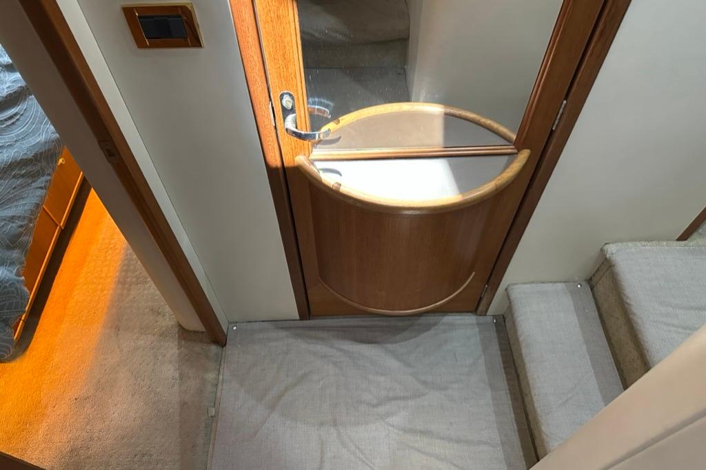 Interior of 1999 Bayliner 5788 Pilot House Motoryacht with wooden door and carpeted stairs.