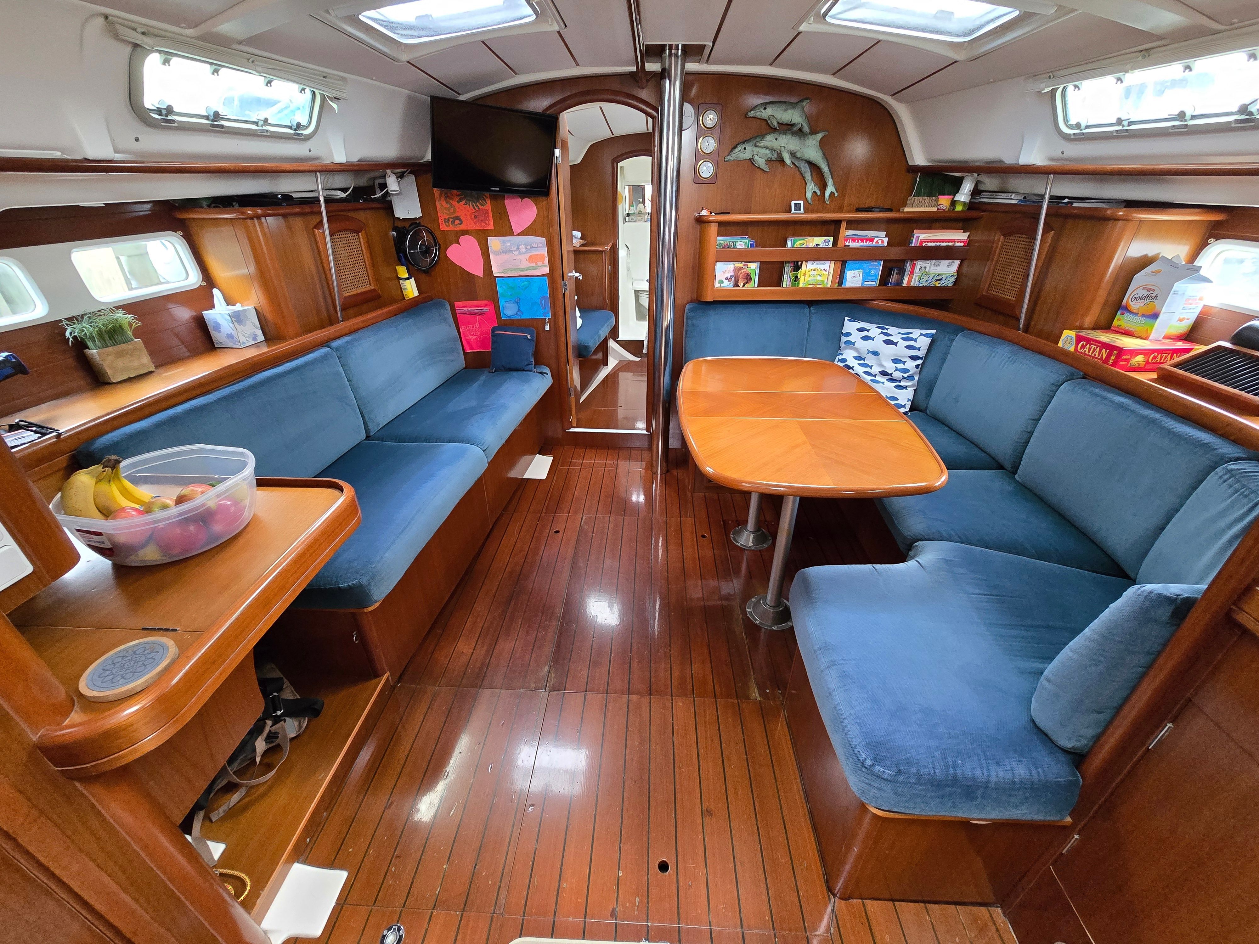 Interior of a 1998 Beneteau 411 with blue upholstery and wooden table.