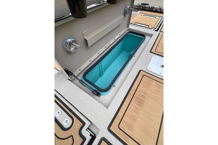 2026 Avid 21 FSX boat storage compartment with teal interior and wood-patterned deck.