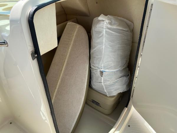 Storage compartment in a 2005 Sea Ray 220 Sundeck boat with cushions and wrapped items.