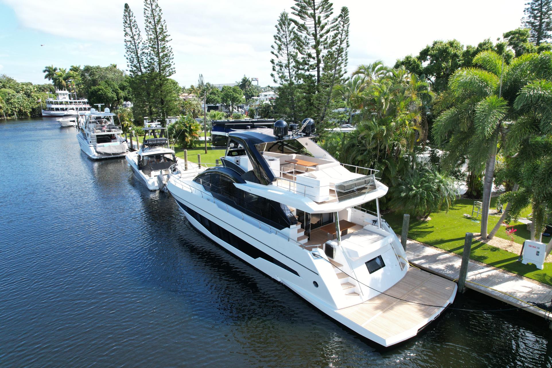 2024 Astondoa 66 Flybridge yacht docked in a scenic marina.