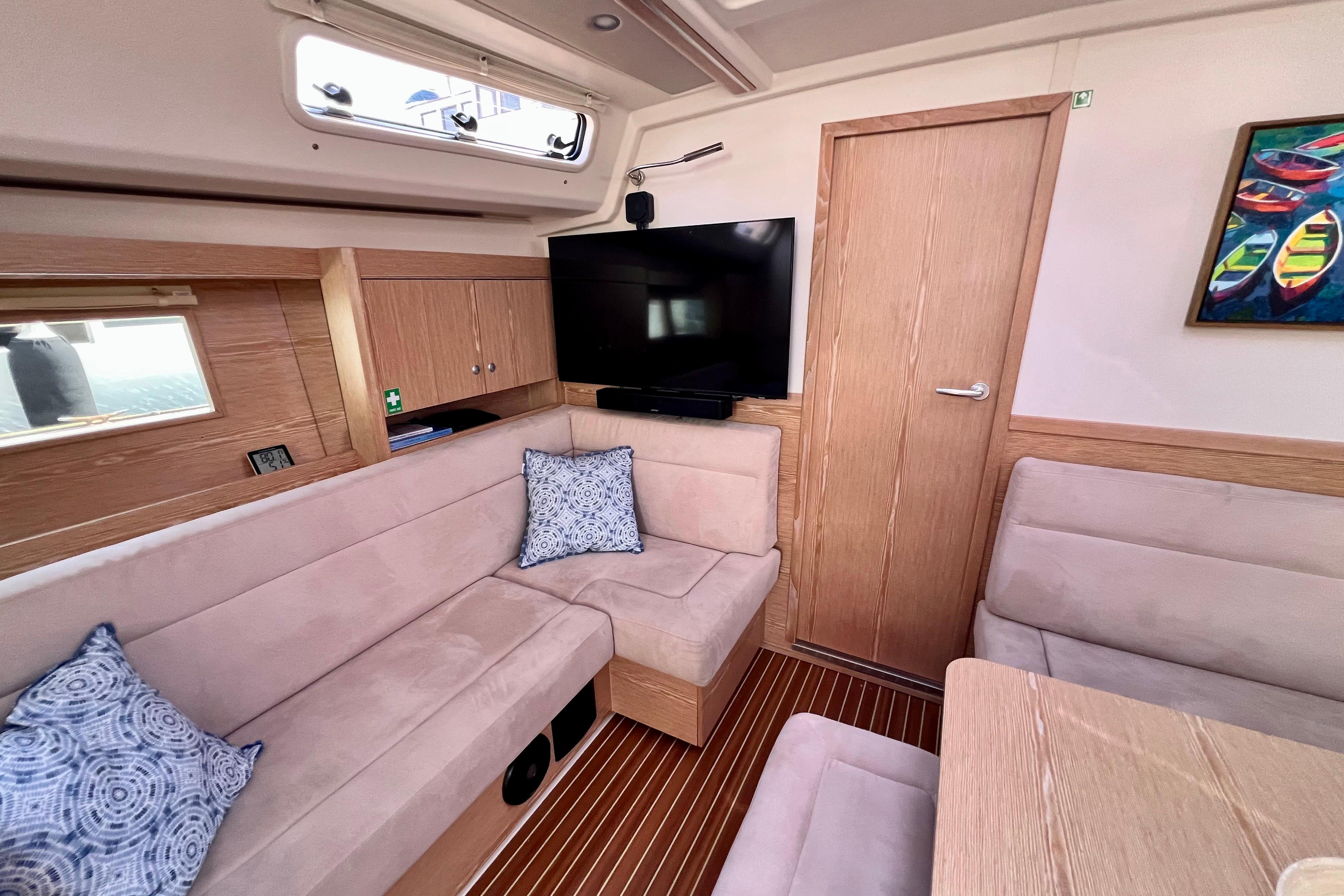 Interior of 2016 Hanse 455 yacht with cozy seating, TV, and nautical decor.