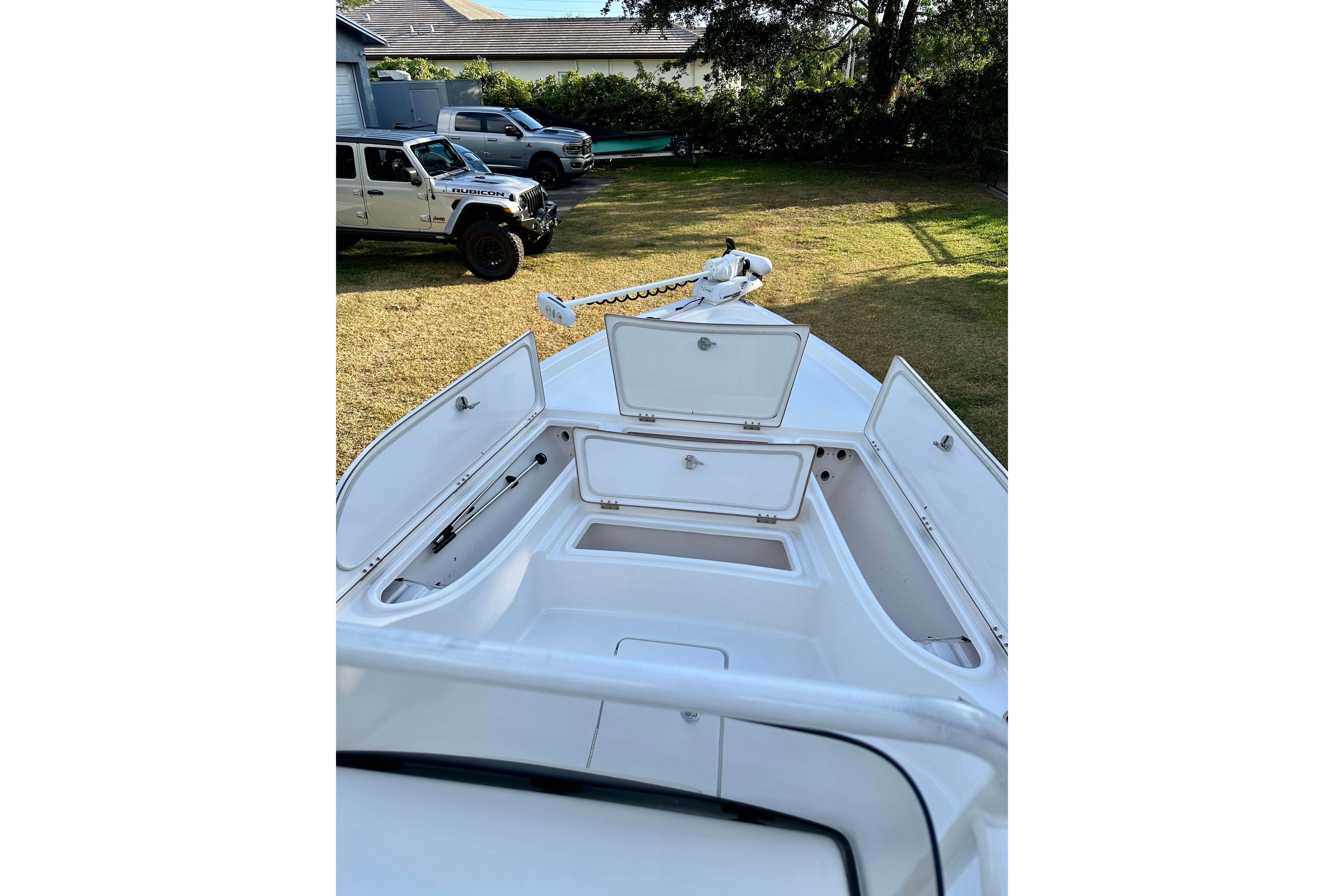 2017 Blue Wave 2400 PureBay boat with open storage compartments, parked on grass.