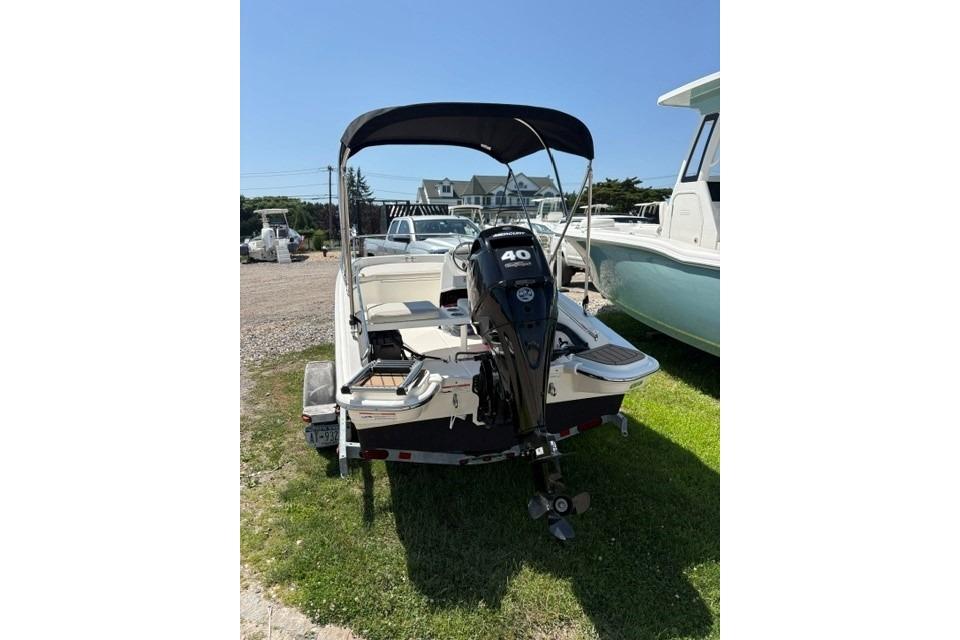 2024 Boston Whaler 130 Super Sport boat with outboard motor, parked on grass.