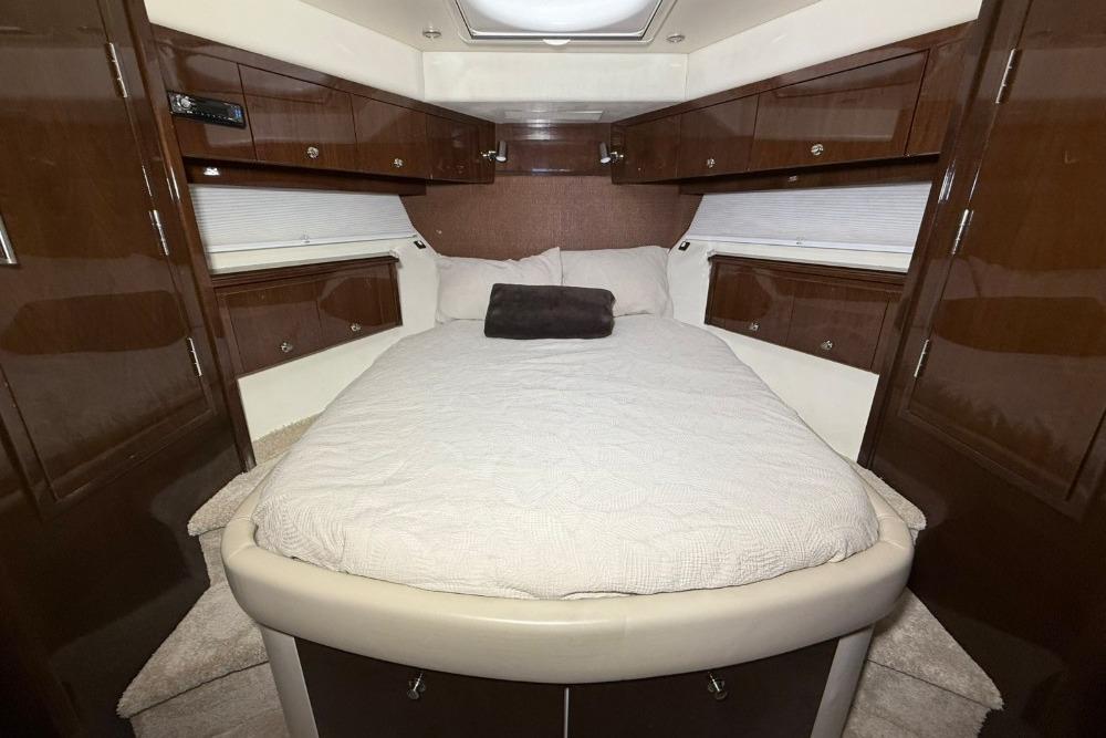 Luxurious bedroom interior of a 2007 Marquis 55 LS yacht with elegant wood cabinetry.