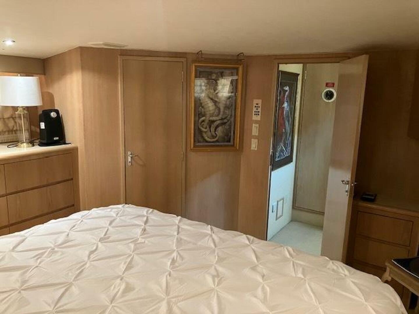 Bedroom interior of 1996 Hatteras 70 Sport Deck Motor Yacht with wood paneling and artwork.