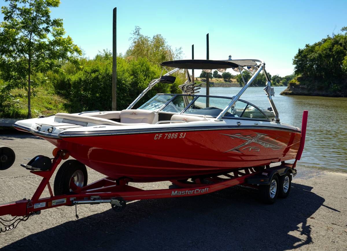 A red 2007 MasterCraft X-45 boat on a trailer near the water.