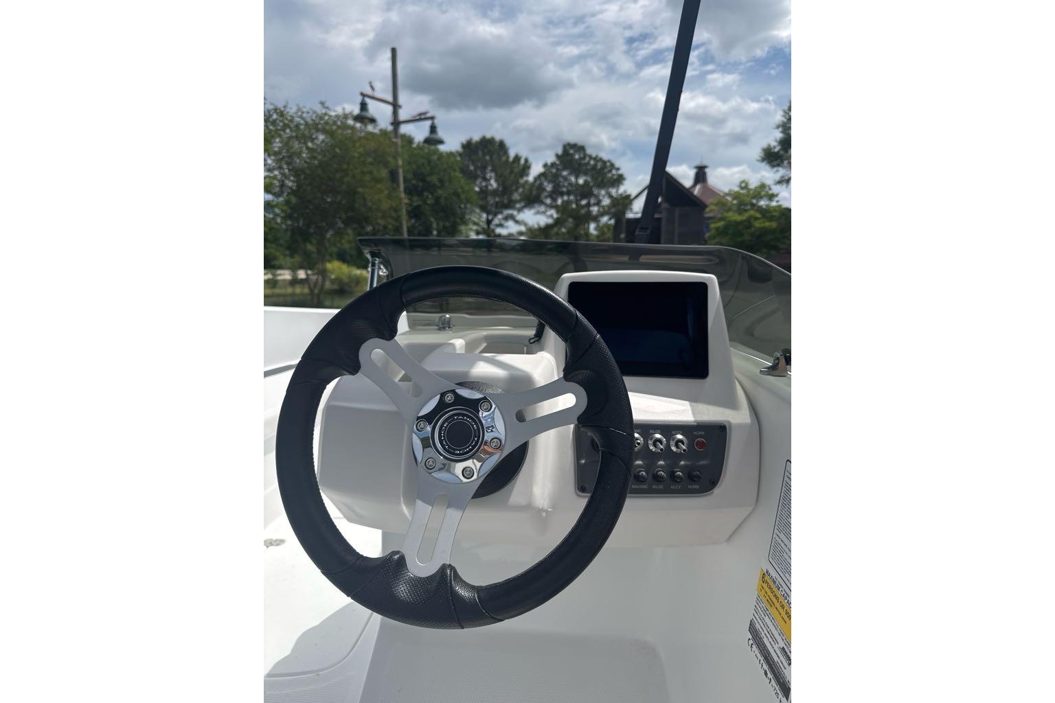 Steering wheel and dashboard of a 2026 Tahoe T16 boat under a cloudy sky.