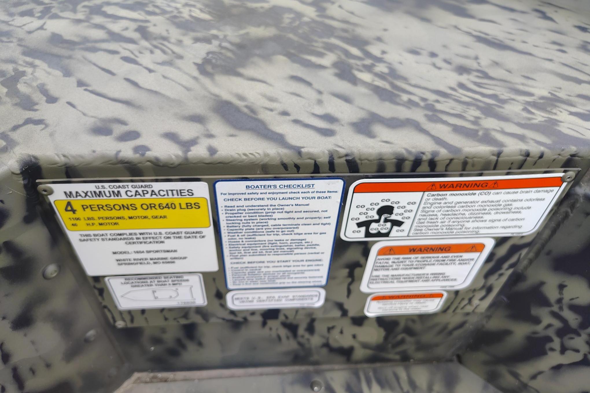 2026 Tracker Grizzly 1654 T Sportsman capacity and safety labels on camouflage surface.