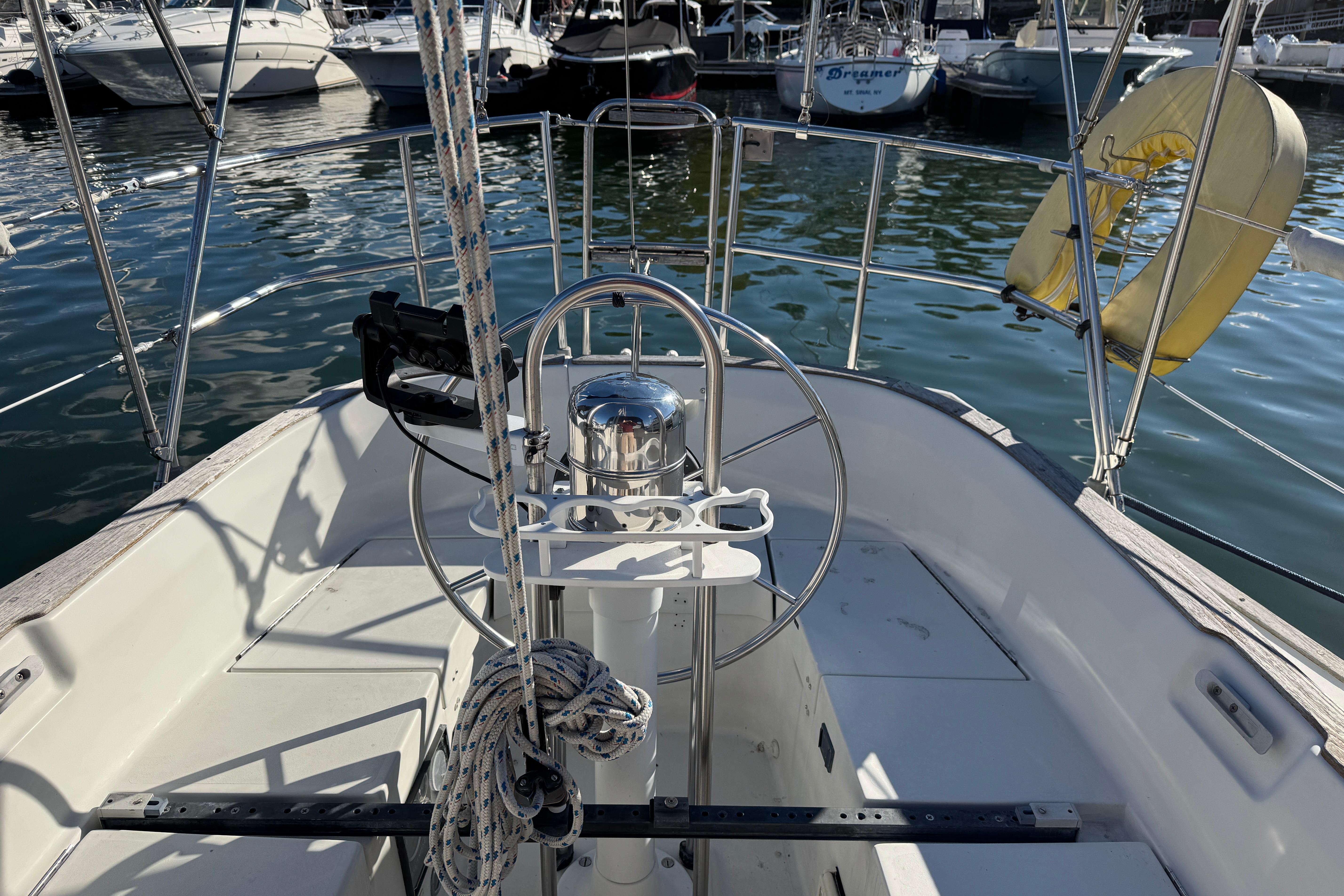 Cockpit of a 1984 C&C Landfall sailboat with steering wheel and marina view.