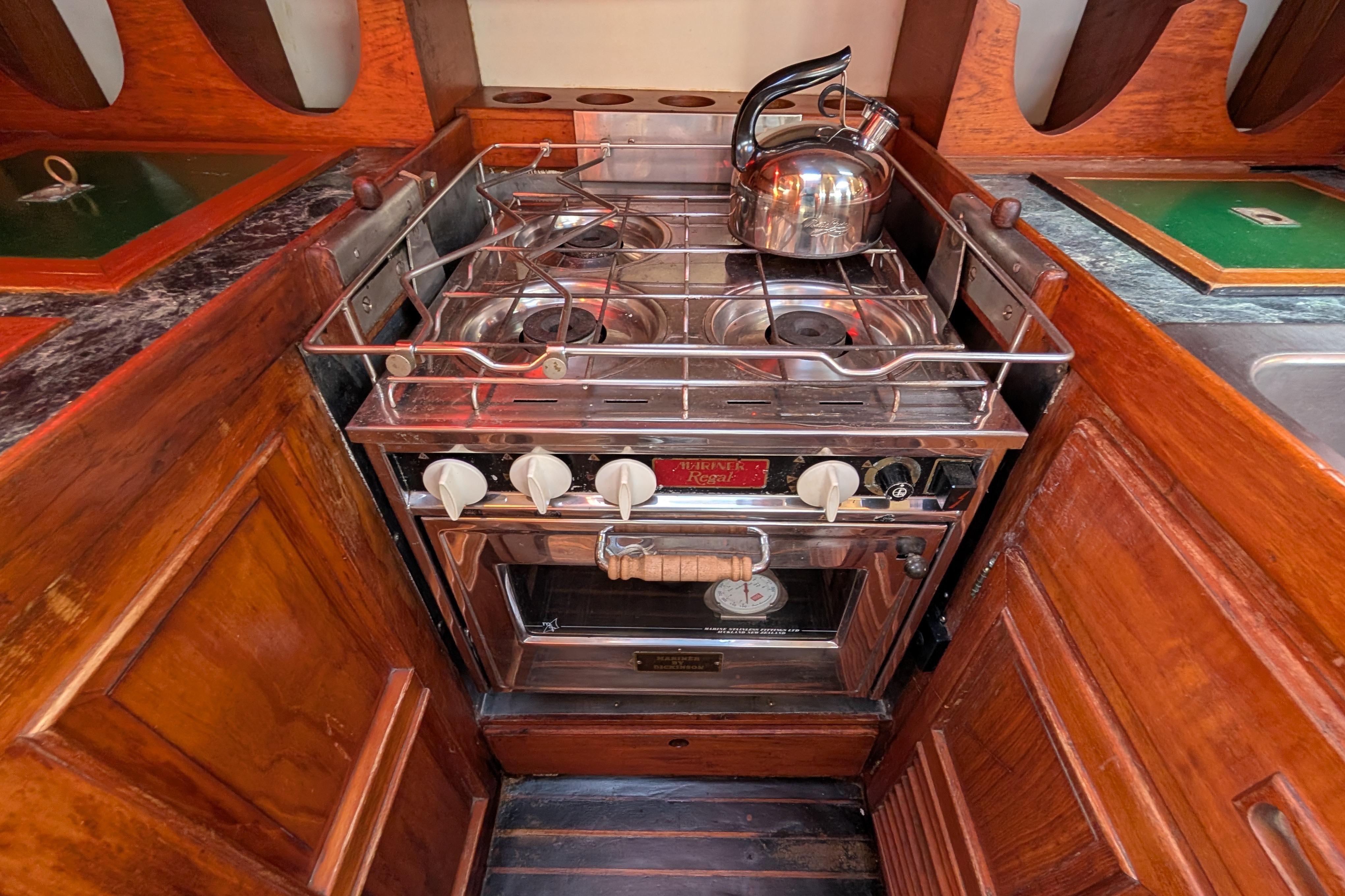 Compact galley kitchen with stove and kettle on a 1983 Robert Perry 41 yacht.
