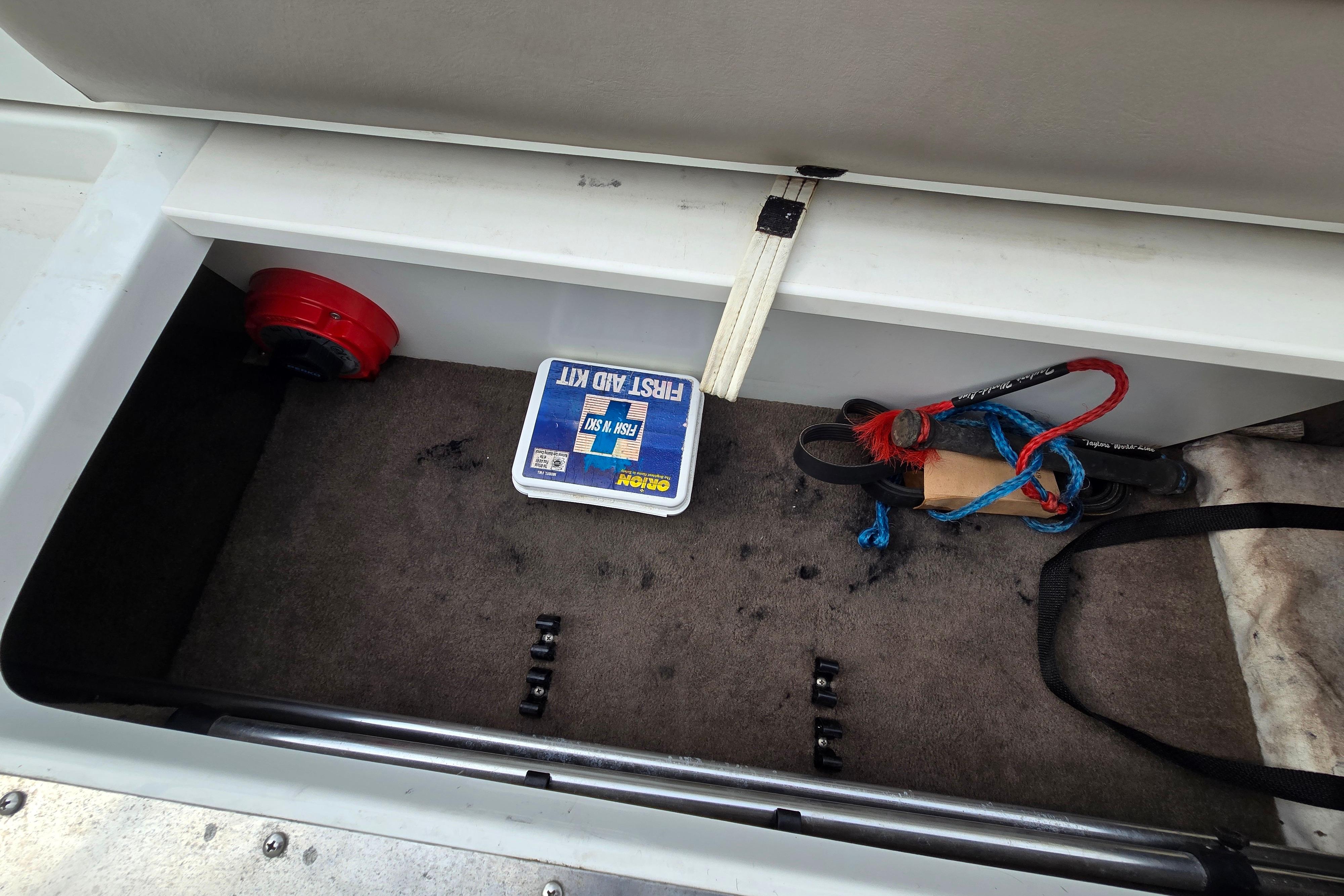 Storage compartment in a 2000 Cobalt 246 boat with first aid kit and ropes.