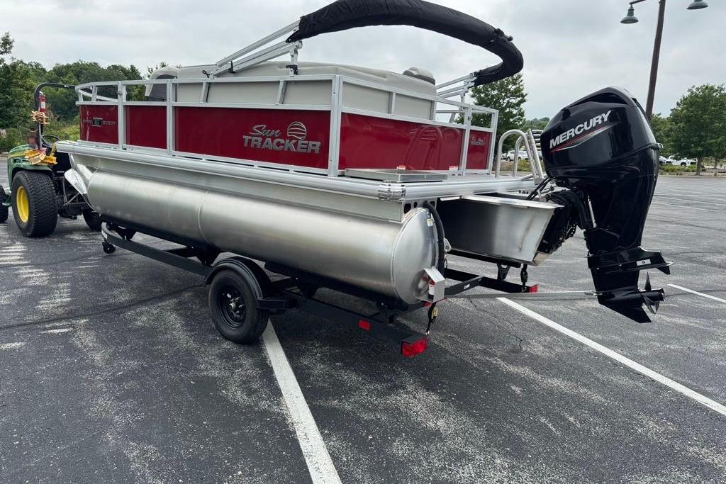 2026 Sun Tracker Bass Buggy 16 XL Select pontoon boat with Mercury outboard motor in parking lot.