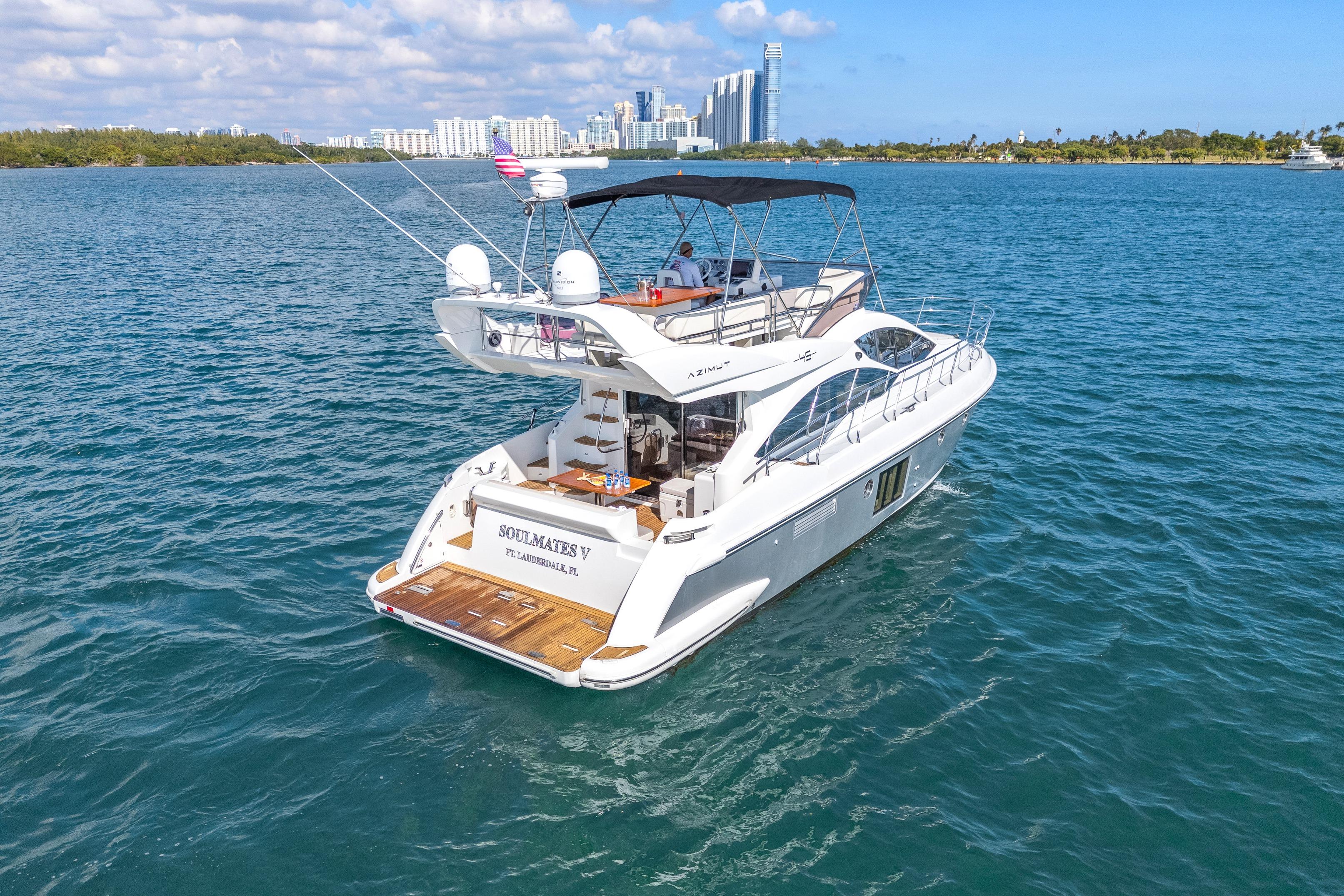 2013 Azimut 45 Flybridge yacht cruising near city skyline on a sunny day.