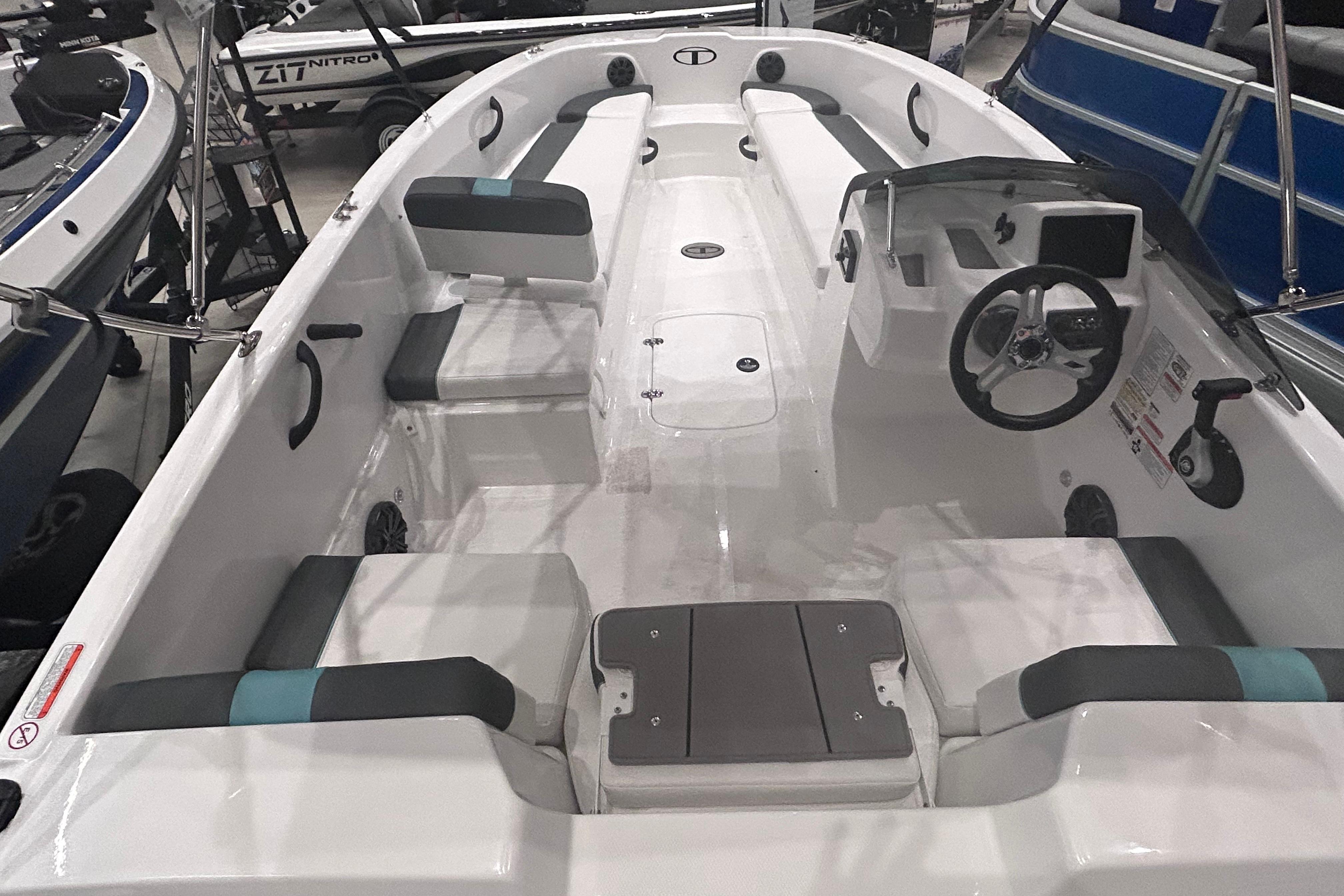 2026 Tahoe T18 boat interior with seating and steering console, displayed in a showroom.