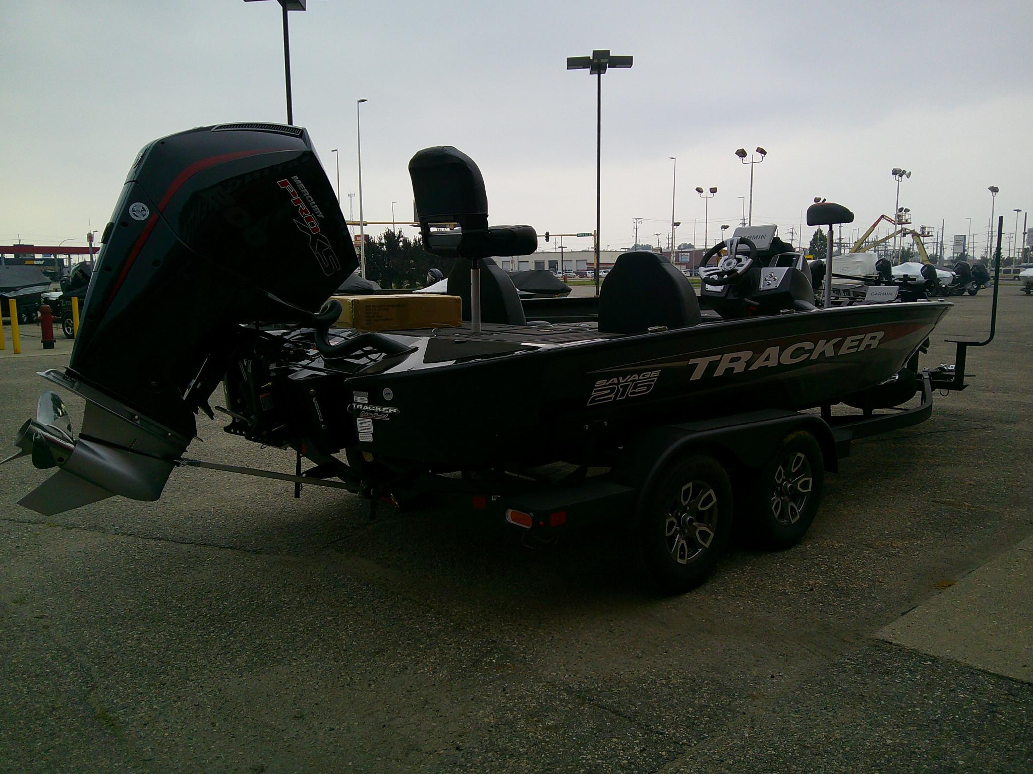 2025 Tracker Savage 215 boat on trailer, parked outdoors, featuring powerful outboard motor.