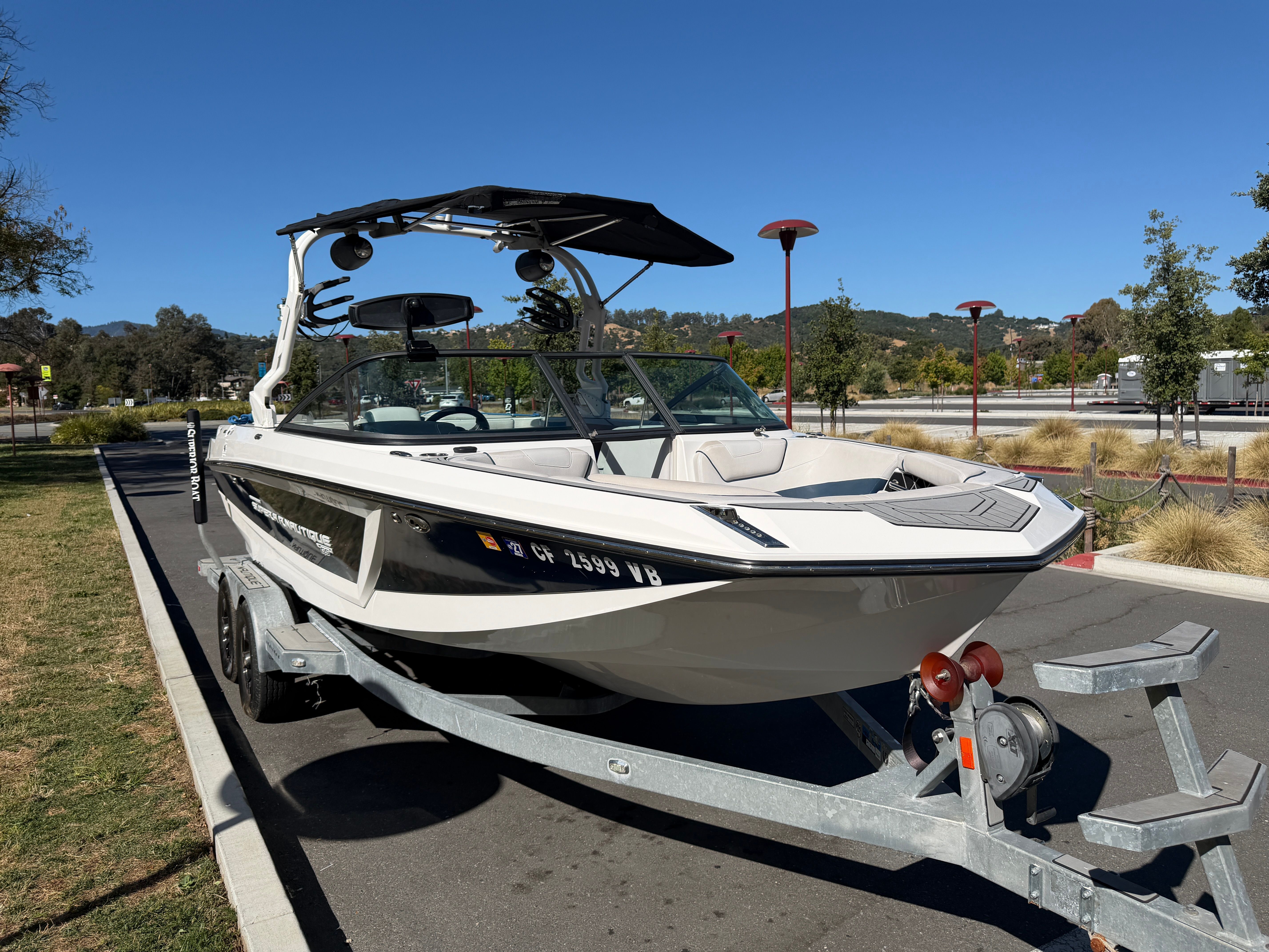 A 2018 Nautique Super Air Nautique GS22 on a trailer, parked on a street.
