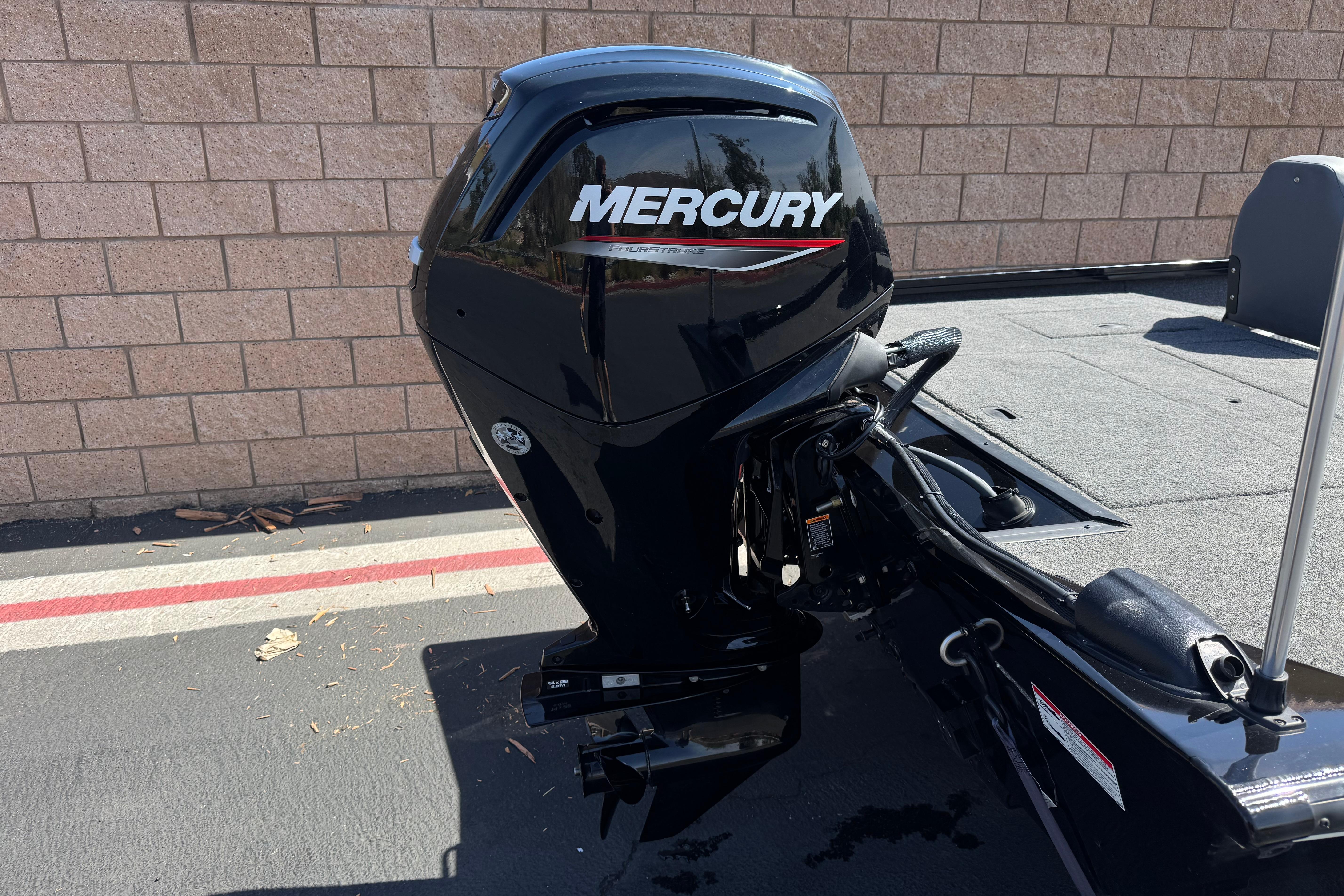 2024 Lowe Stinger 175 boat with Mercury outboard motor, parked on pavement.