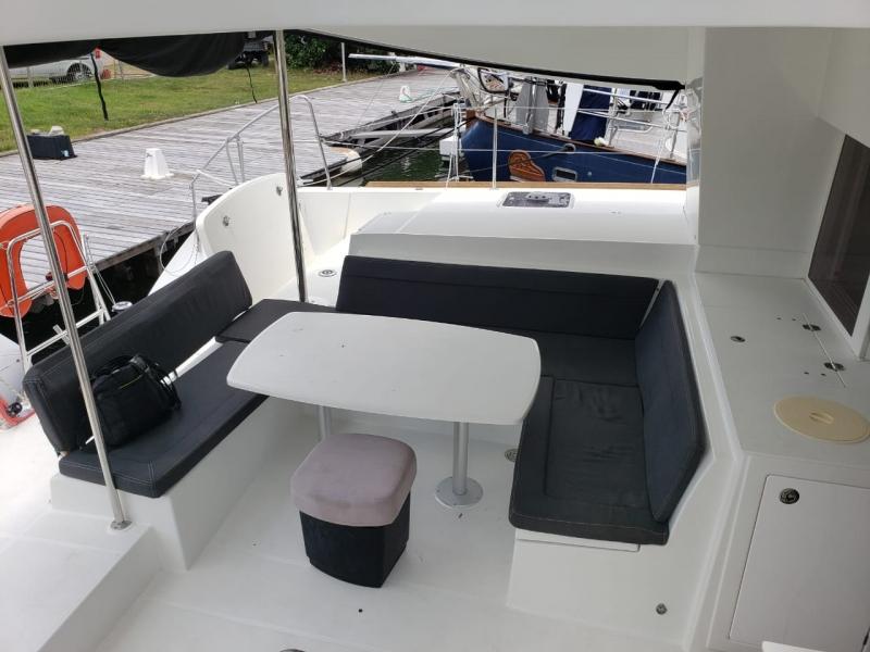 2017 Lagoon 450S yacht with outdoor seating and table near a dock.