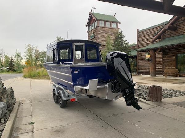 2023 Spartan 220 Maximus Pro boat on trailer near rustic lodge.