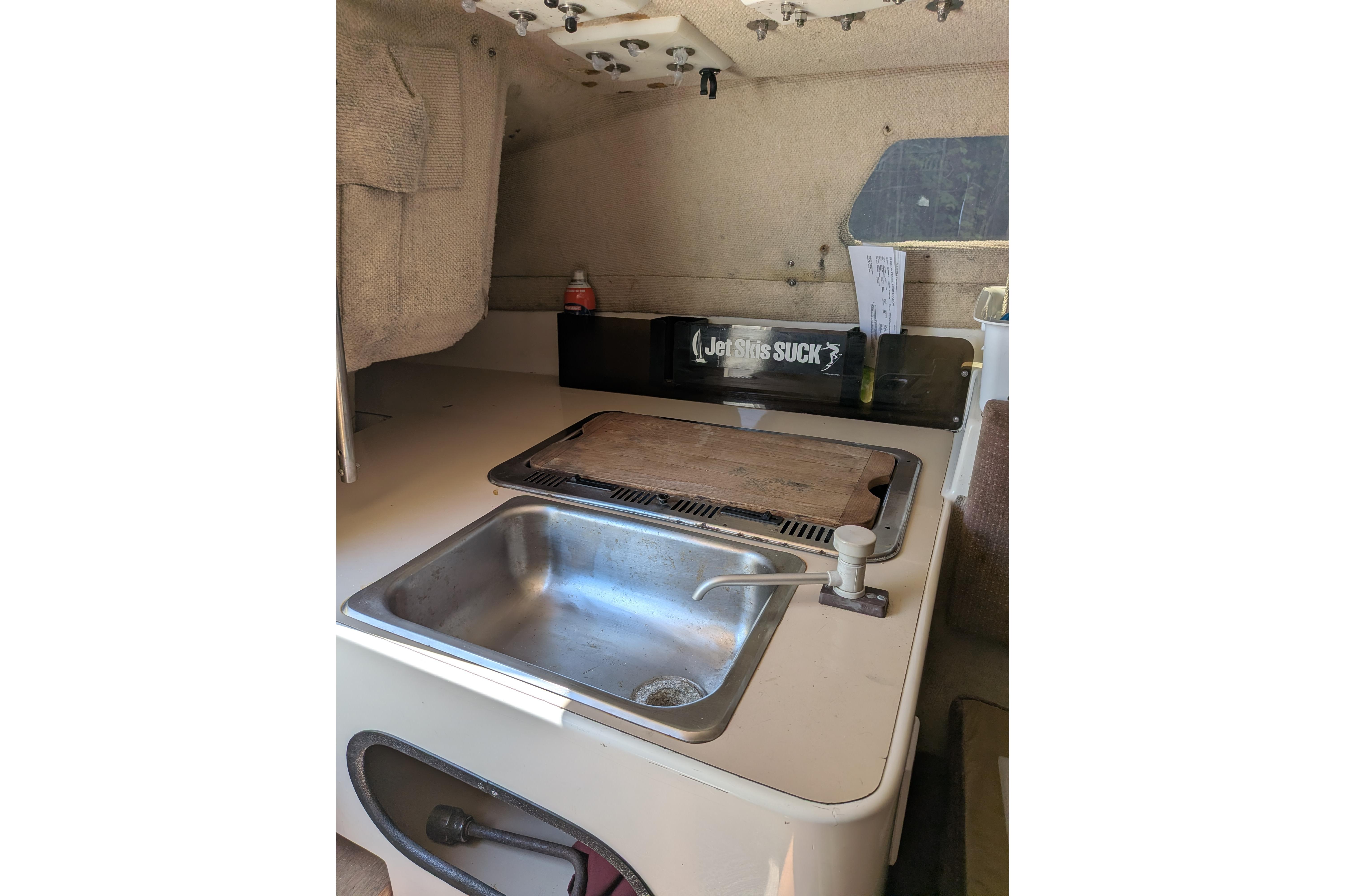 Interior of 1991 Corsair F-27 sailboat with compact kitchen sink and counter.